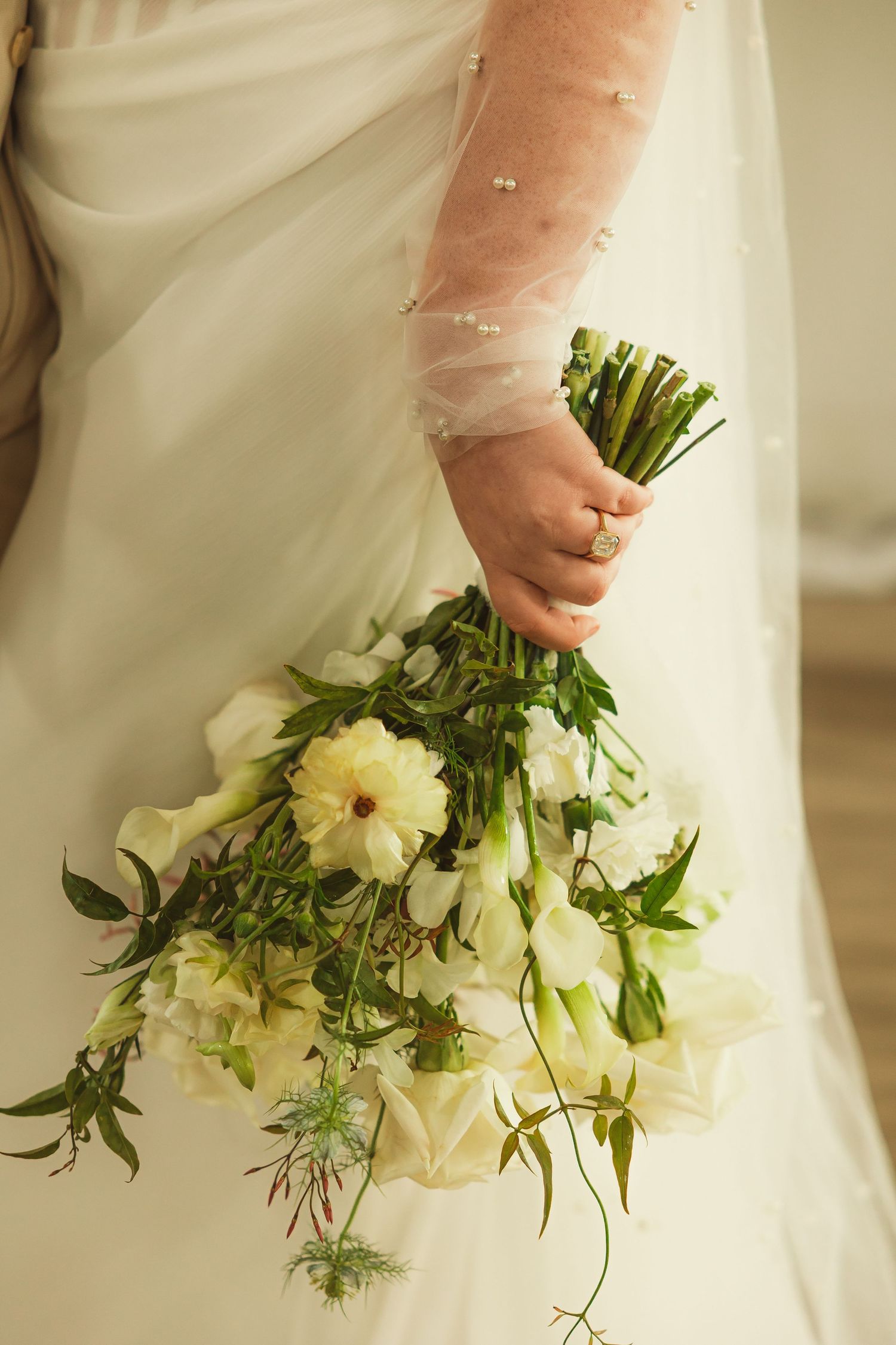 Close-up of white and green wedding bouquet with flowing greenery.