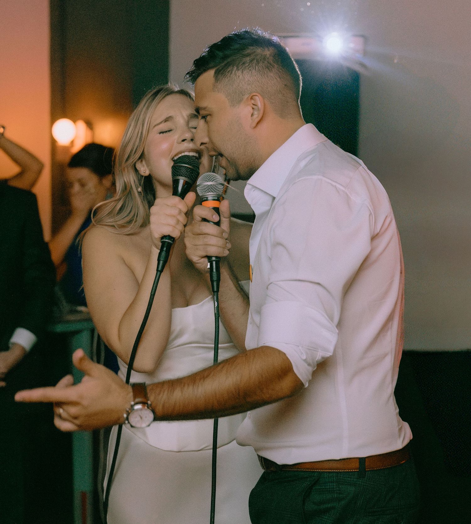Couple sharing a joyful moment while singing karaoke at their wedding reception.