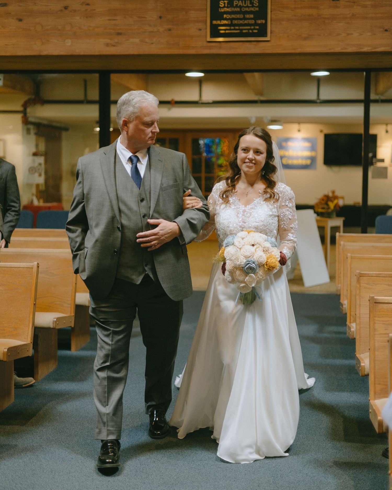 A wedding ceremony in a church with wooden pews and stained glass windows showing a couple during the service.