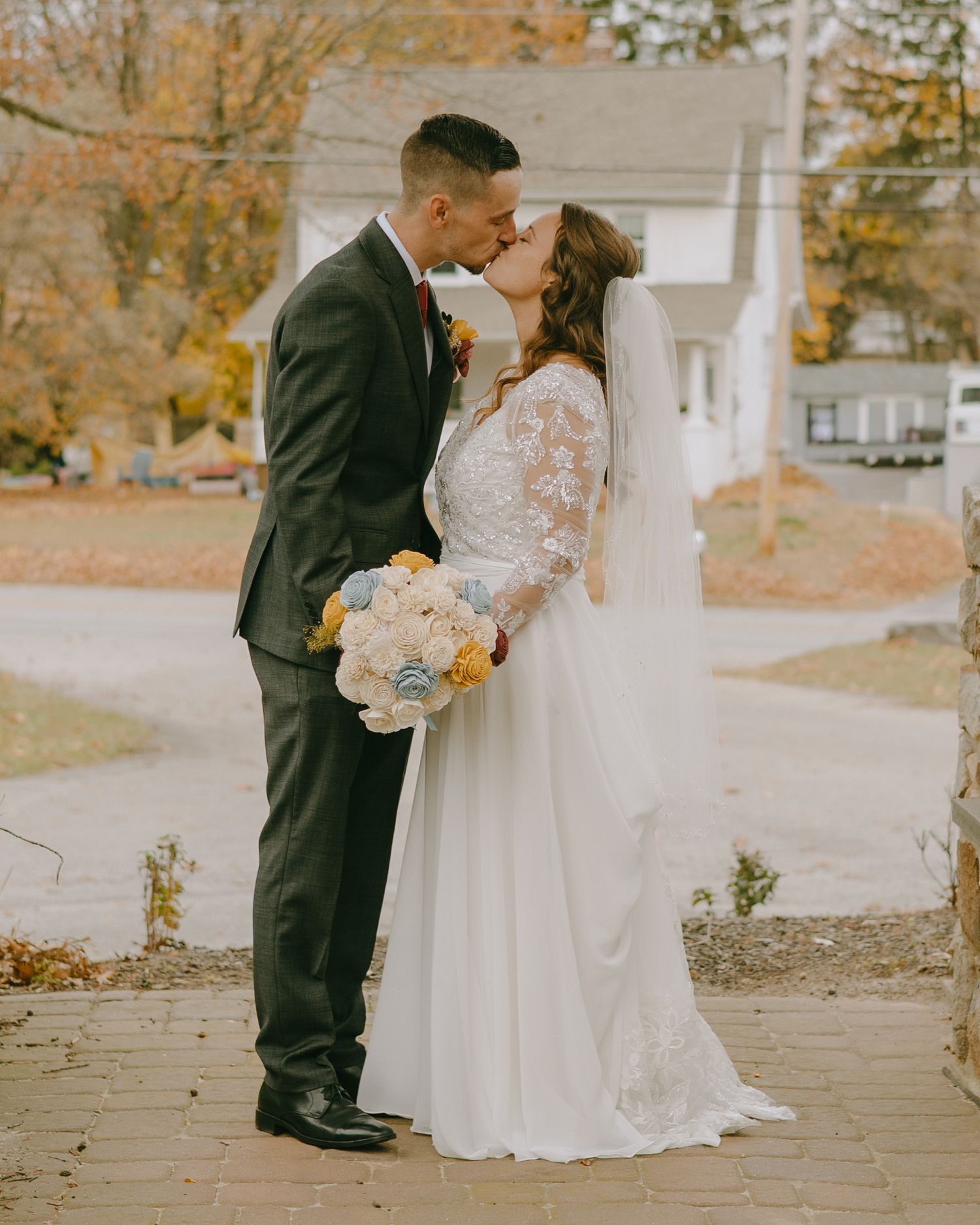 A couple shares intimate moments in their wedding attire during an autumn outdoor photoshoot.