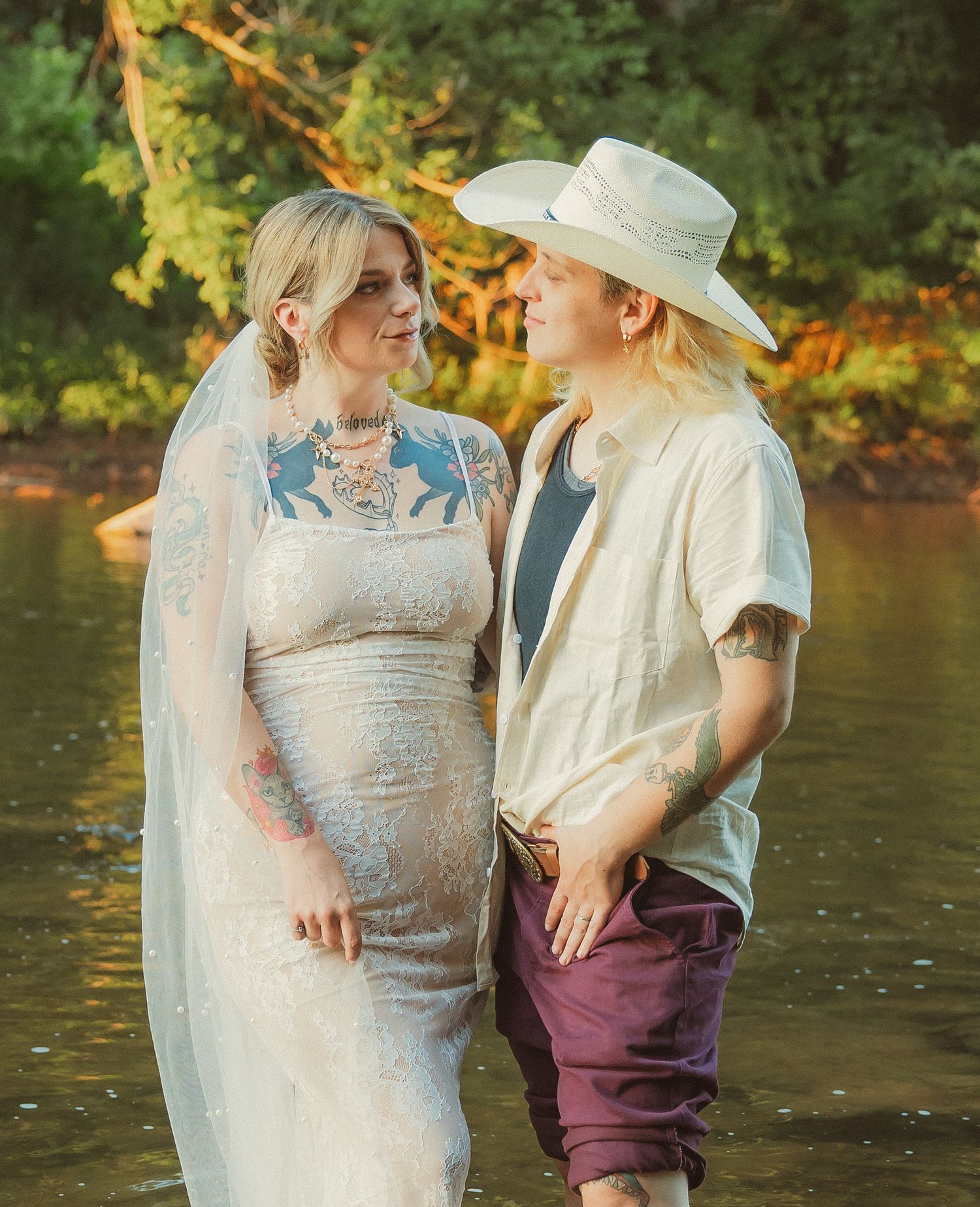 A romantic riverside photoshoot featuring a wedding dress and casual attire in golden evening light.
