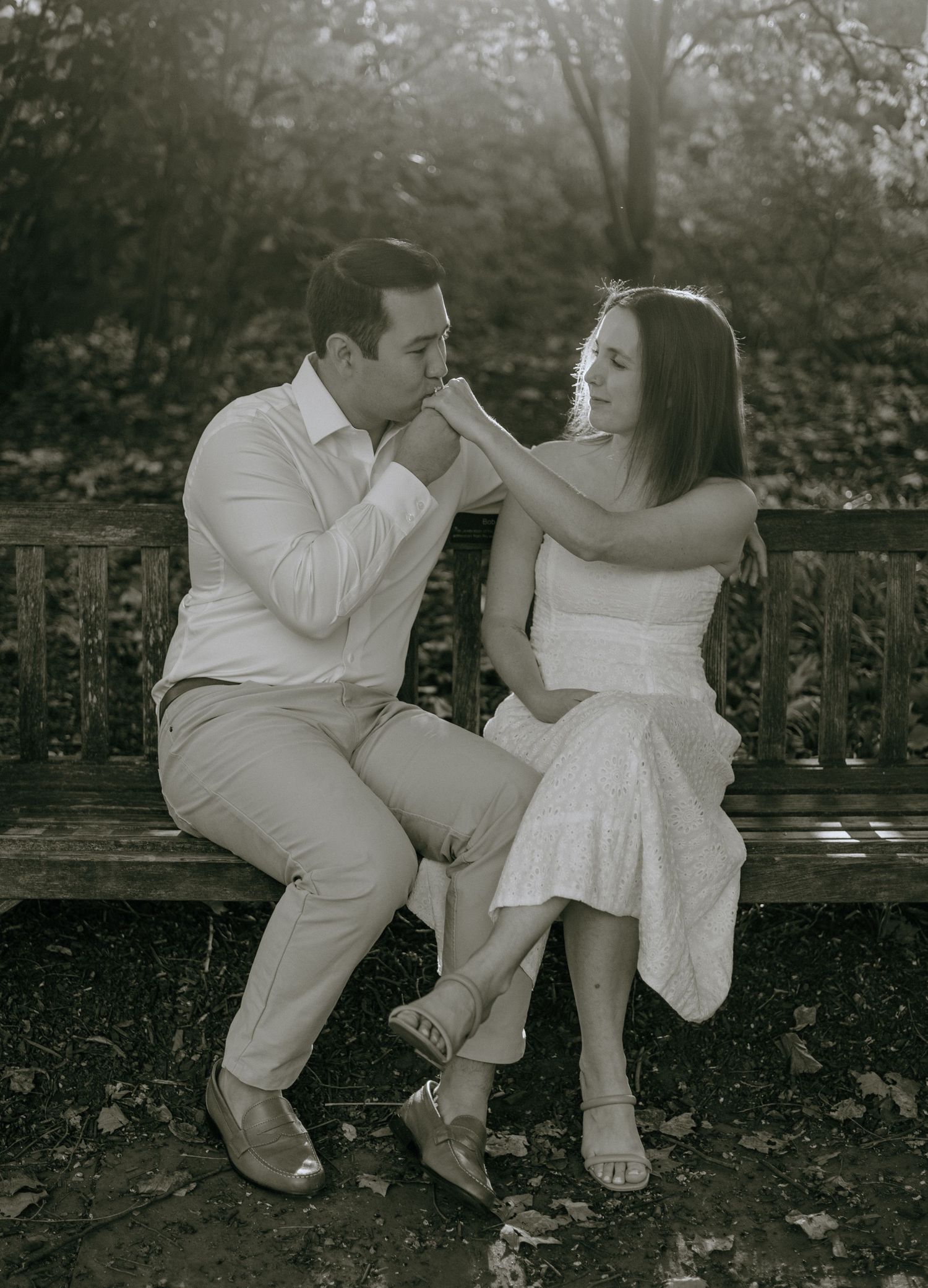 Black and white photo of a couple sitting close together on stone steps in an intimate moment.