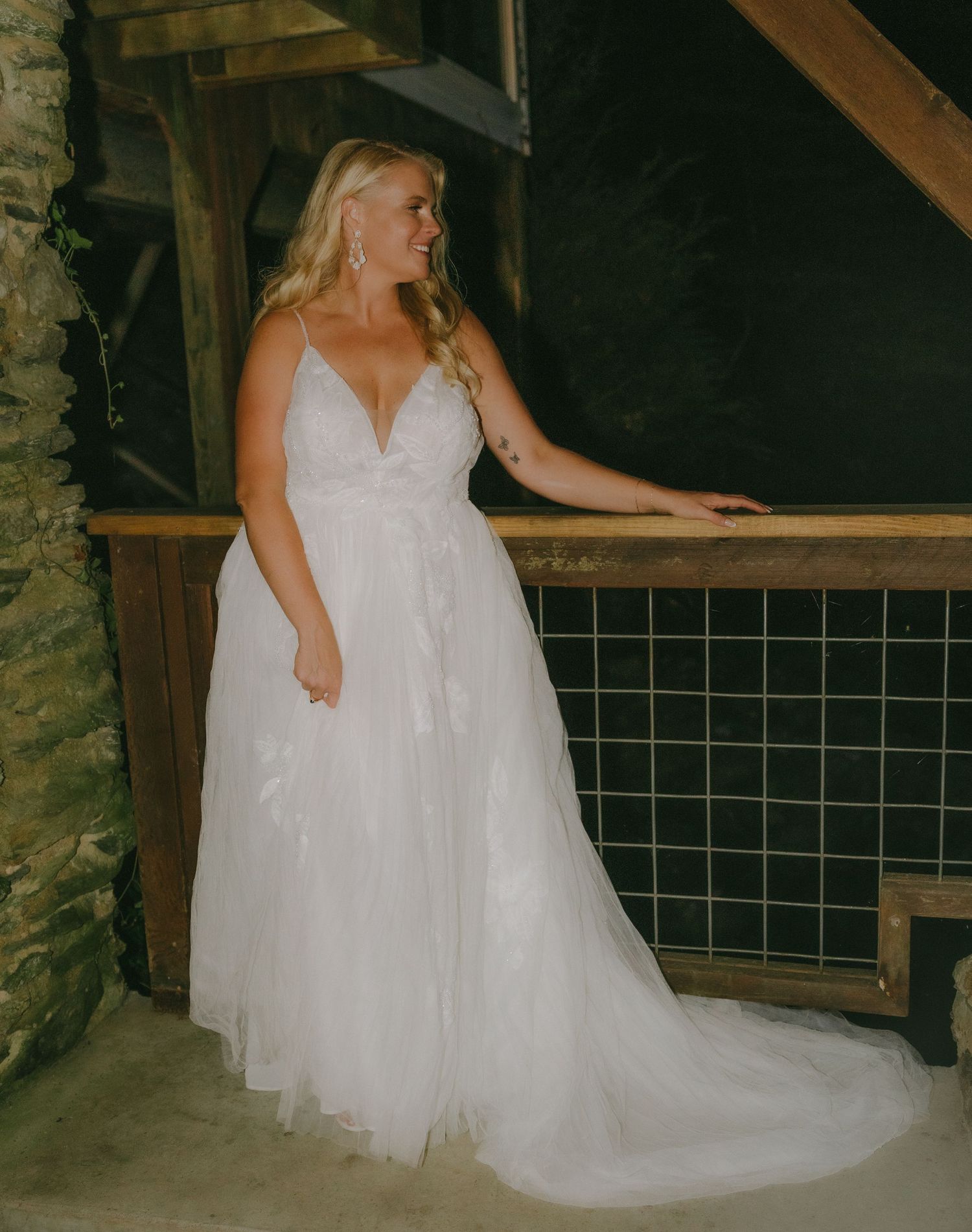 A beautiful white wedding dress twirls in a rustic stone-walled room.