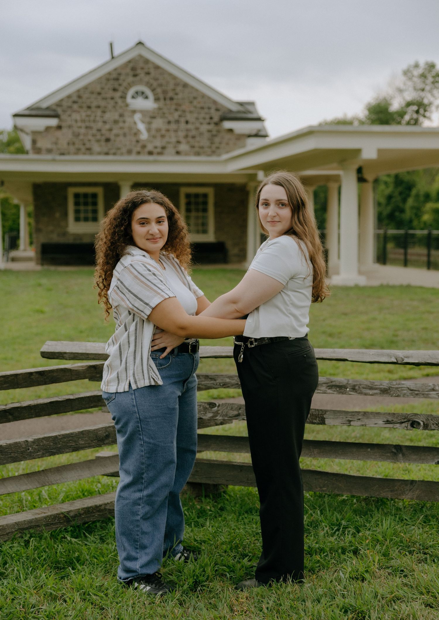 Friends posing together by a white wooden fence near a historic building.