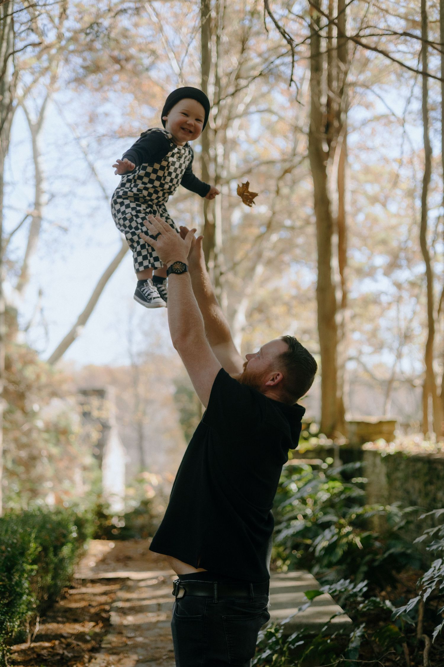 Joyful outdoor scenes of lifting and playing in a sunlit forest setting during fall.