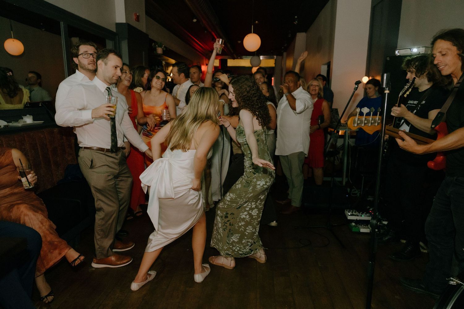 Group of party attendees dancing and enjoying themselves at a dimly lit indoor event.