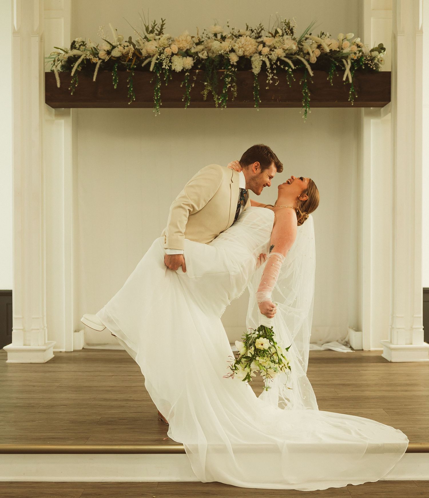 An ethereal bridal photoshoot in a light-filled venue with floral arrangements.