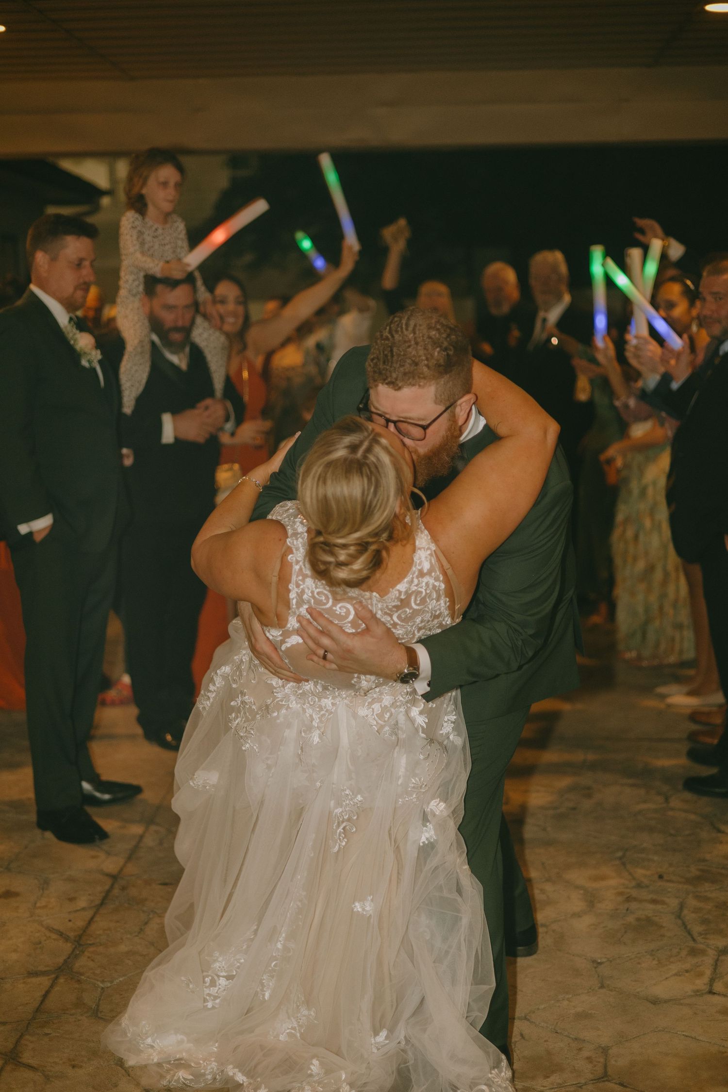 Wedding reception dance floor filled with guests celebrating under colorful lights.