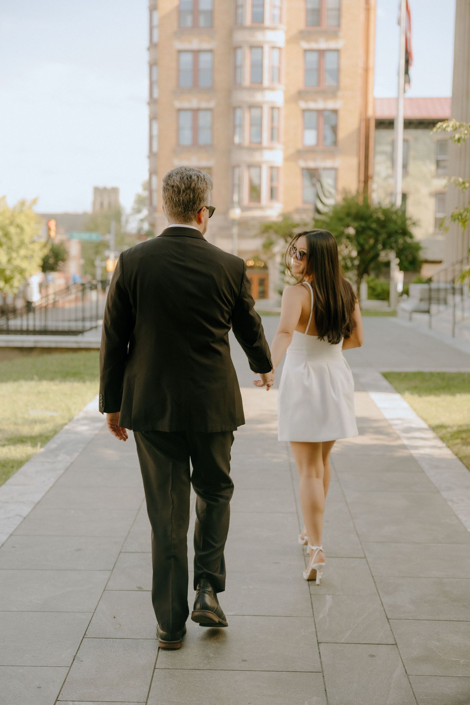 Series showing figures walking along a paved sidewalk with historic buildings in the background.