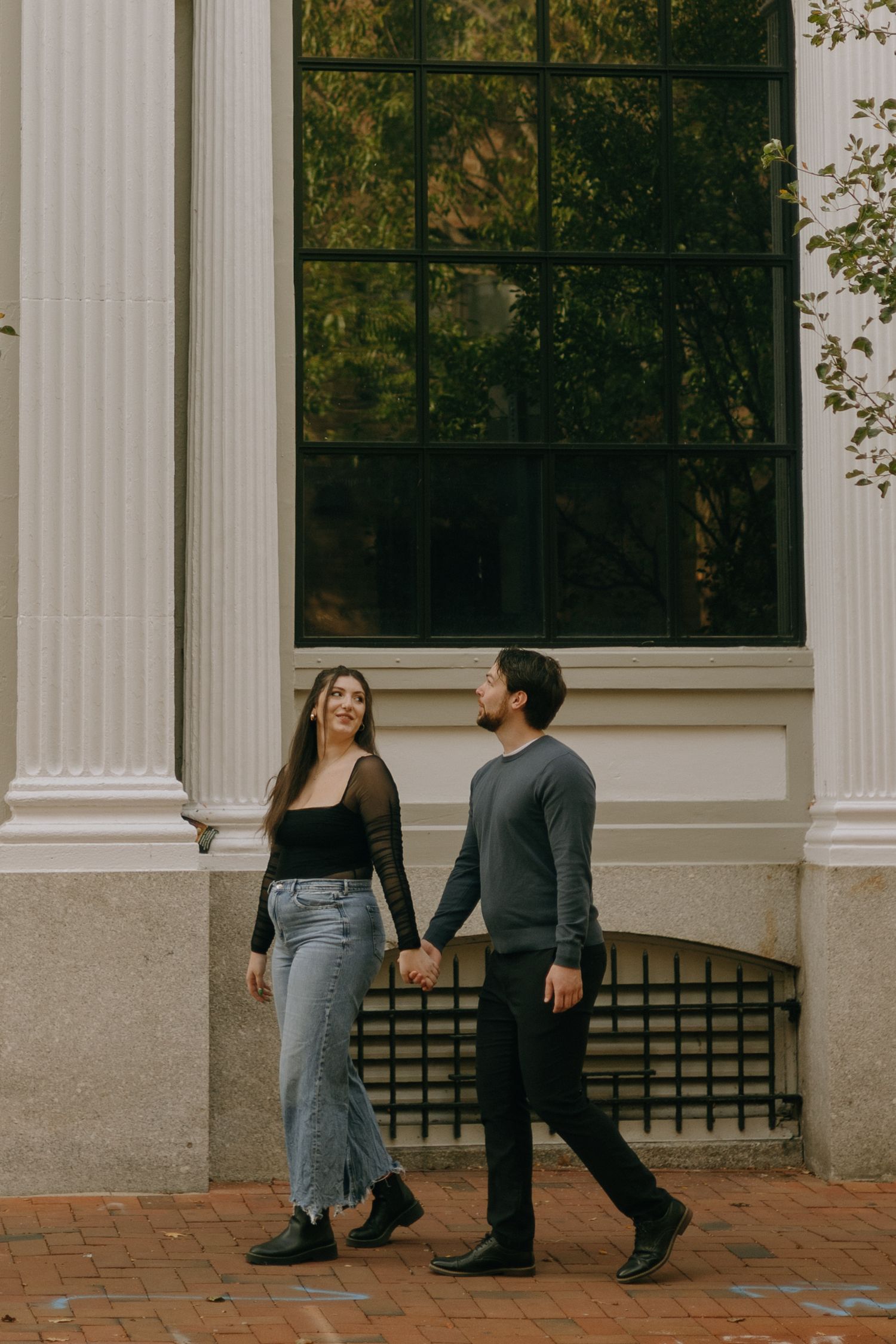 Couple having a tender moment against white columns of a classic building exterior.