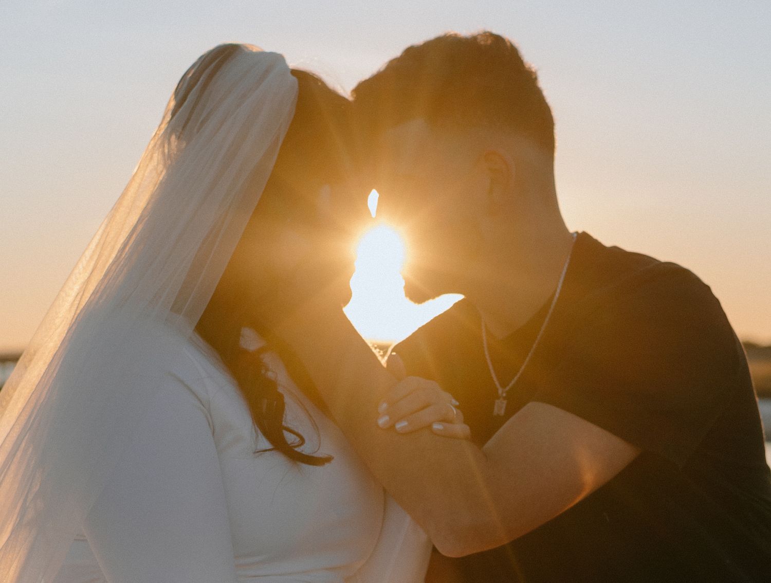 Sunset silhouette of a couple sharing an intimate moment against golden light.