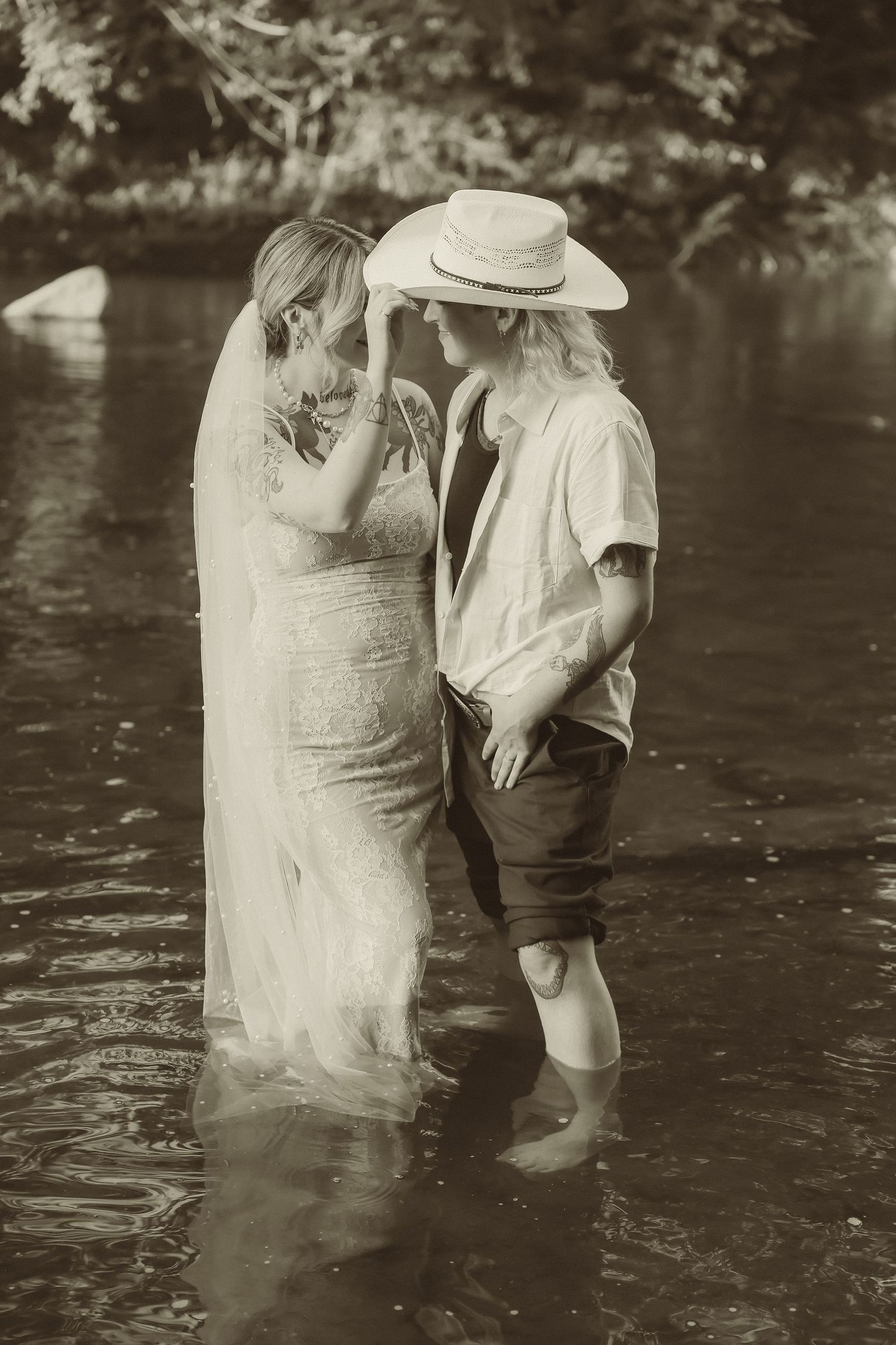 A romantic black and white photo of two people sharing an intimate moment standing in water.