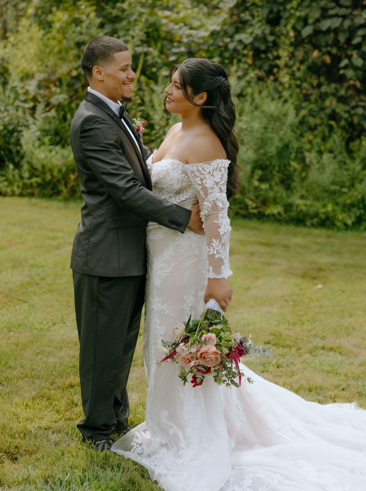 Wedding couple embraces outdoors with bride holding colorful bouquet.