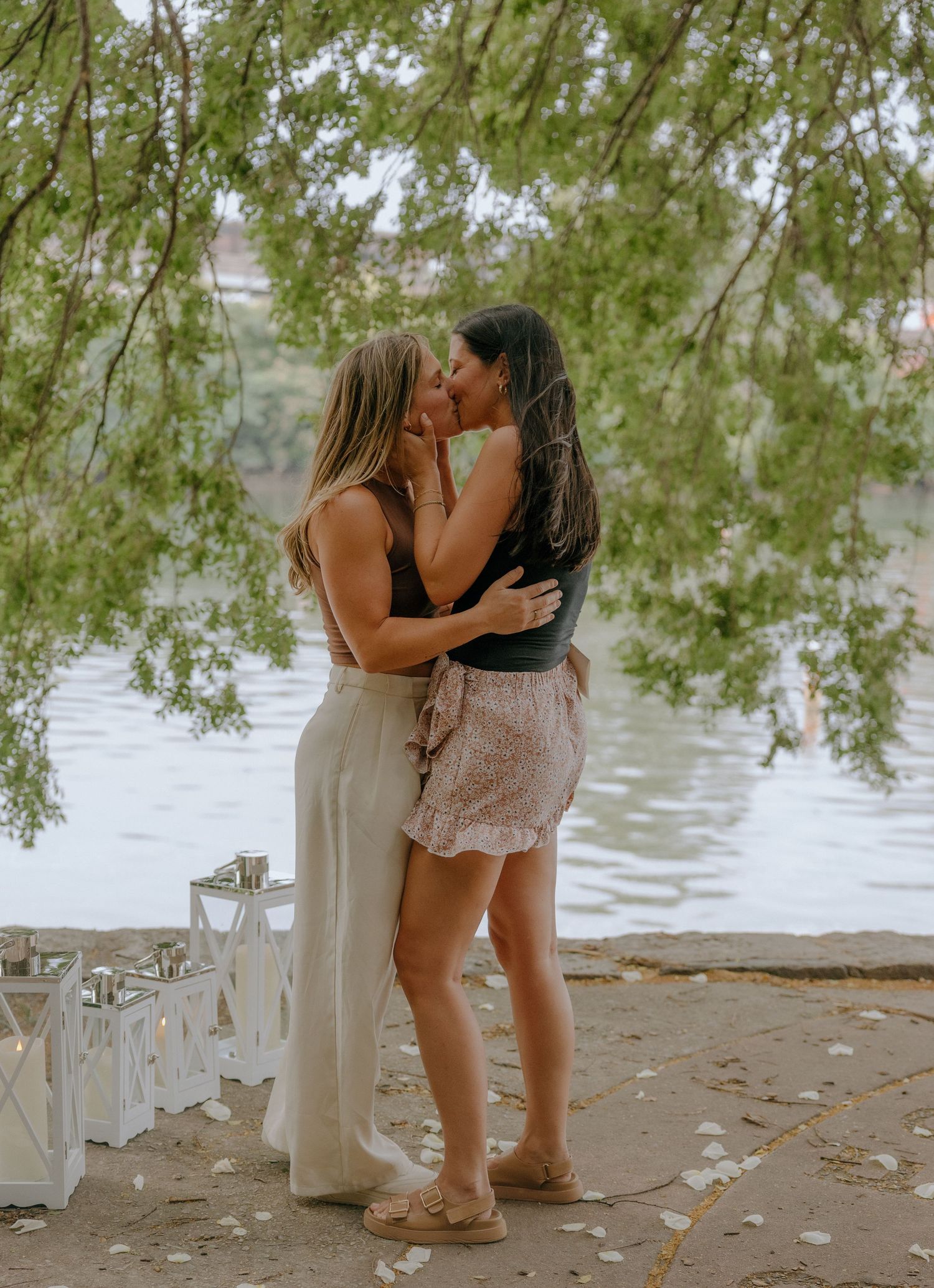 Romantic moments captured along a waterfront path with scattered leaves.