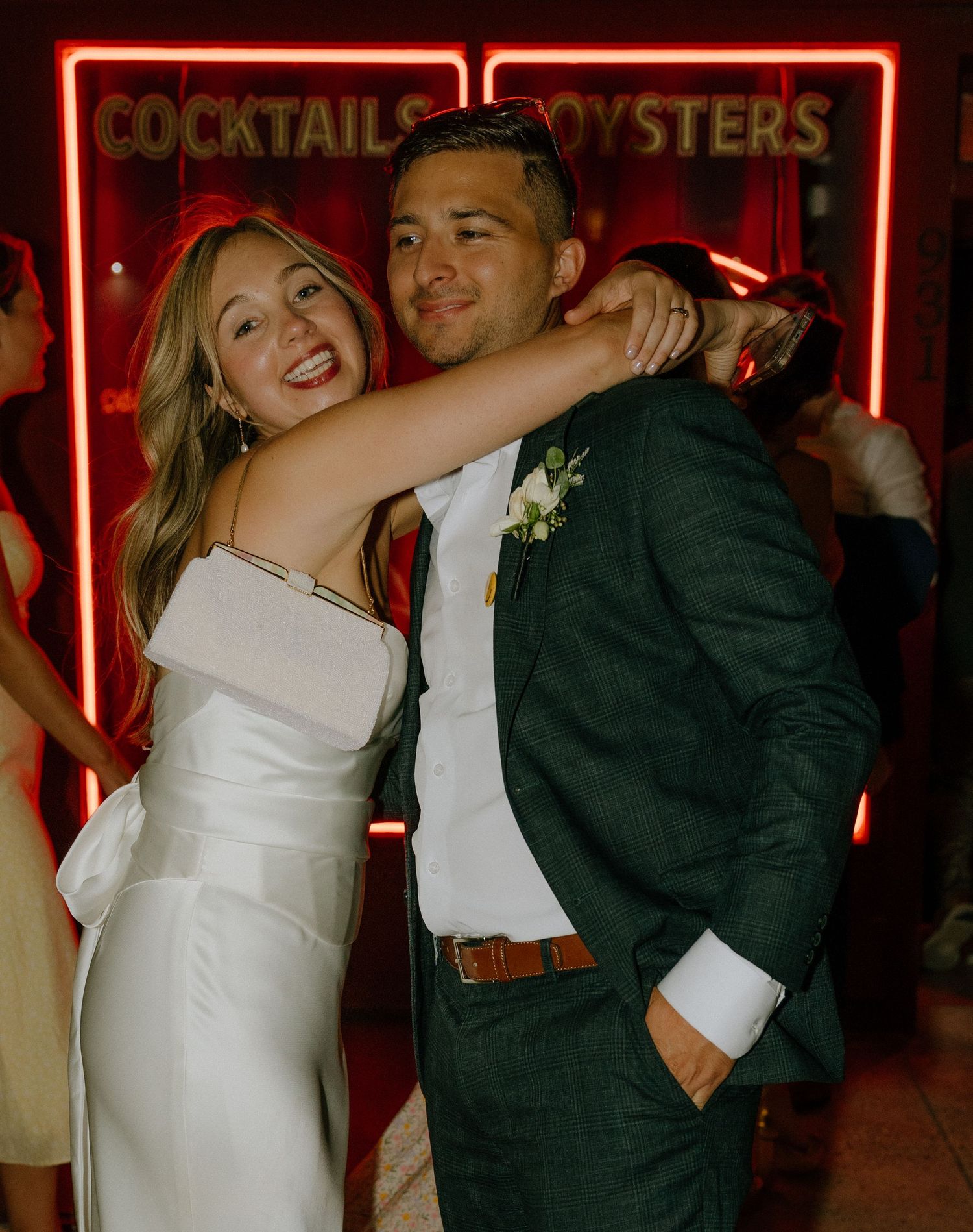 Wedding couple dancing beneath red neon cocktail signs during their reception.