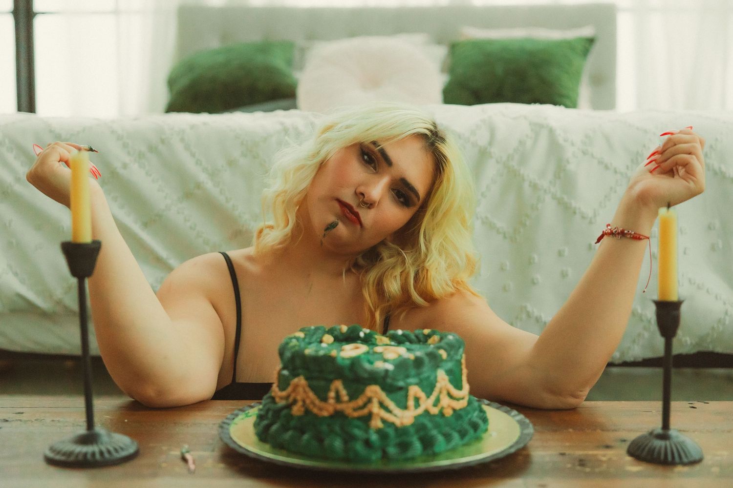 Still life composition with green birthday cake, candles, and decorative table setting.