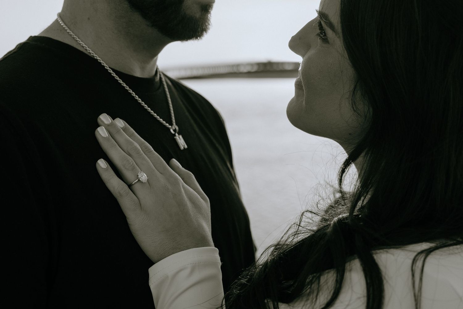 A romantic black and white photo showing a couple in an intimate moment with hands placed on chest.