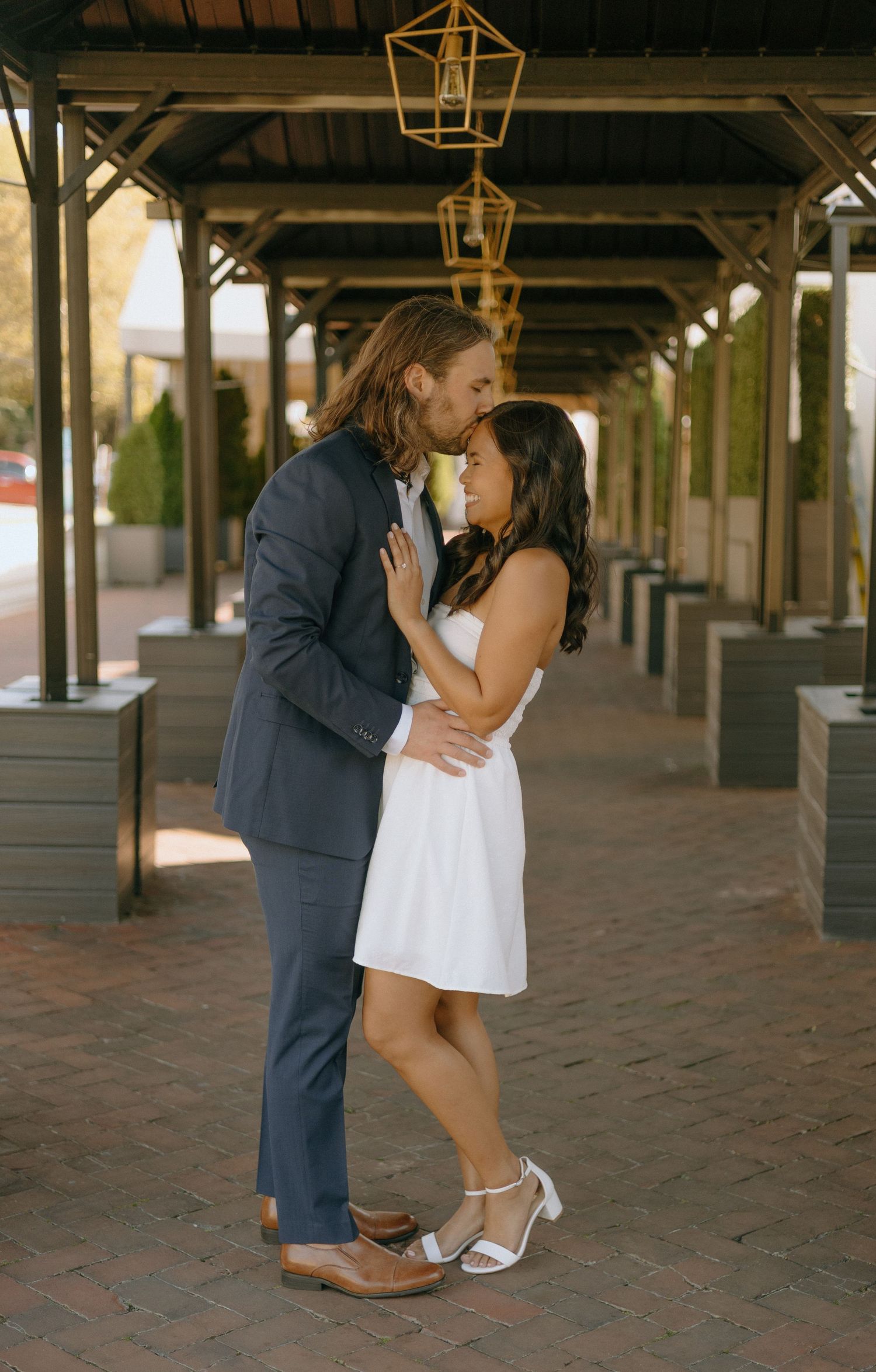 A couple shares romantic moments under a covered walkway with hanging lanterns in a sequence of five photos.