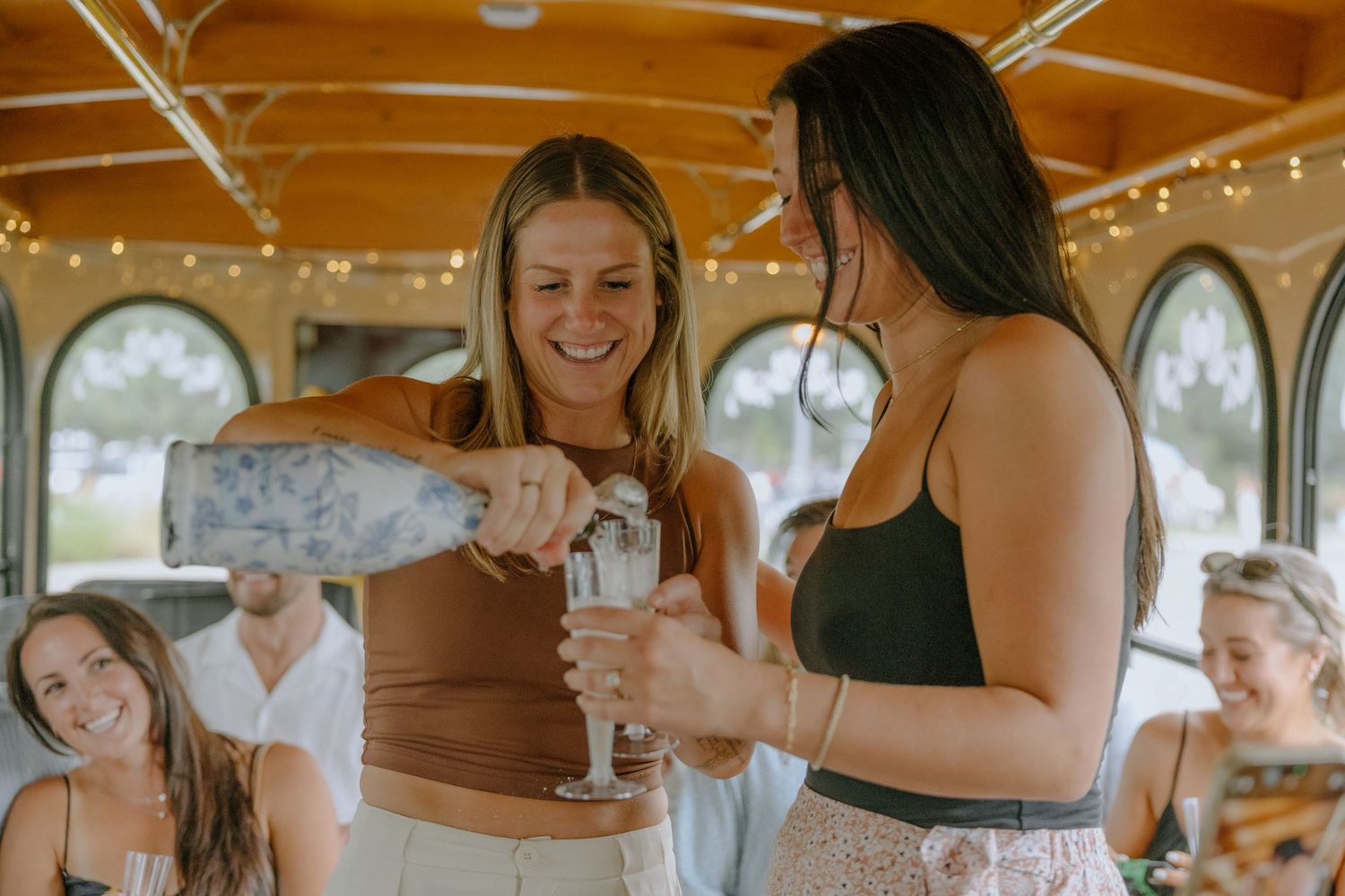 Friends celebrating with drinks inside a rustic venue decorated with string lights.