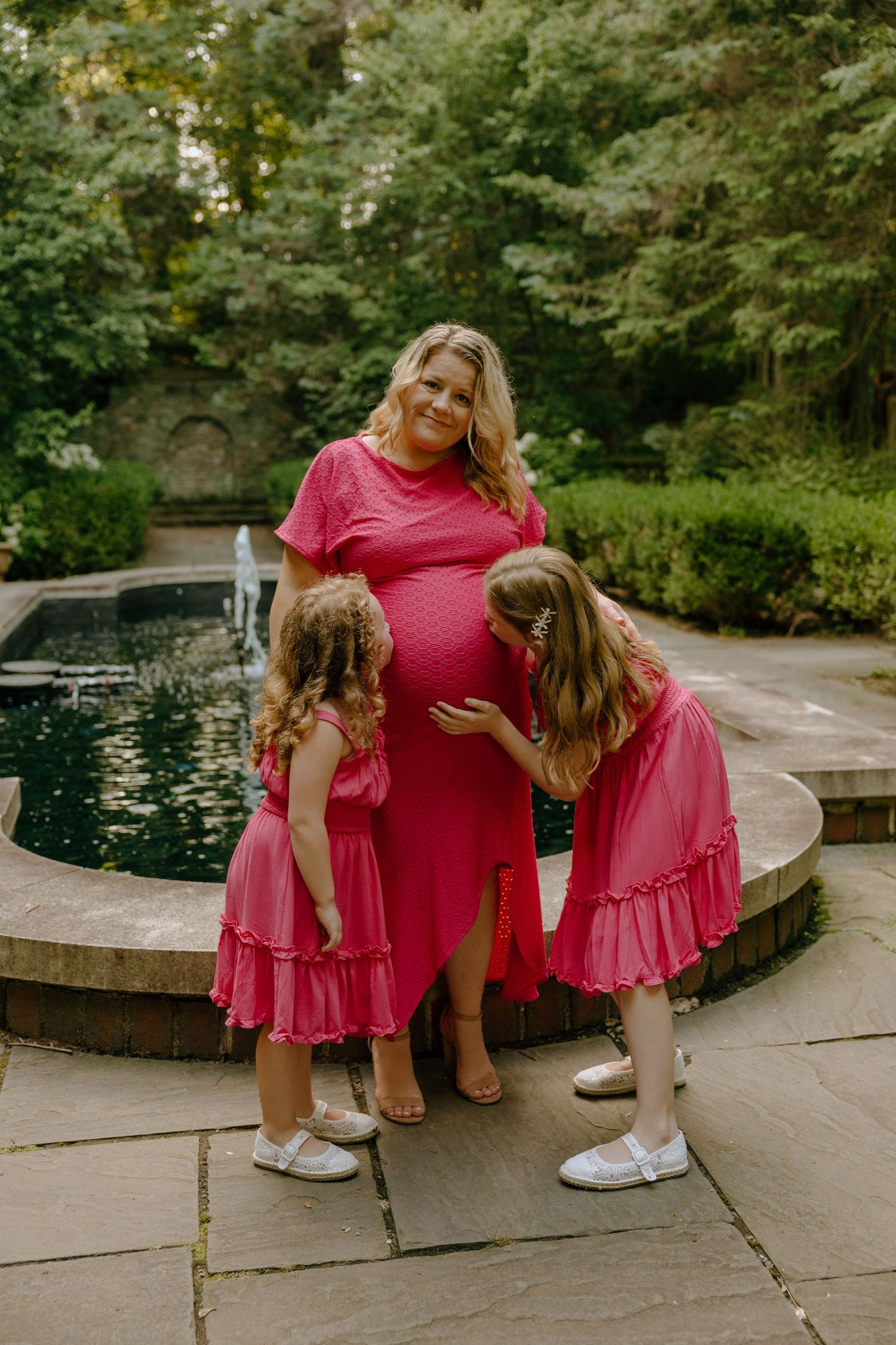Casual family moment captured by curved water feature in coordinated pink outfits.