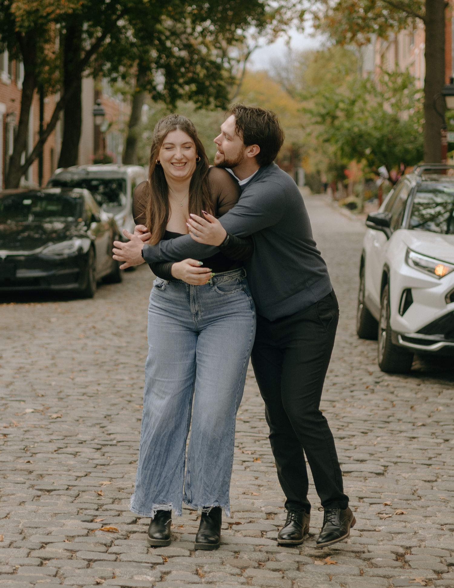 Candid sequence showing a couple sharing a lighthearted moment on a tree-lined cobblestone street.