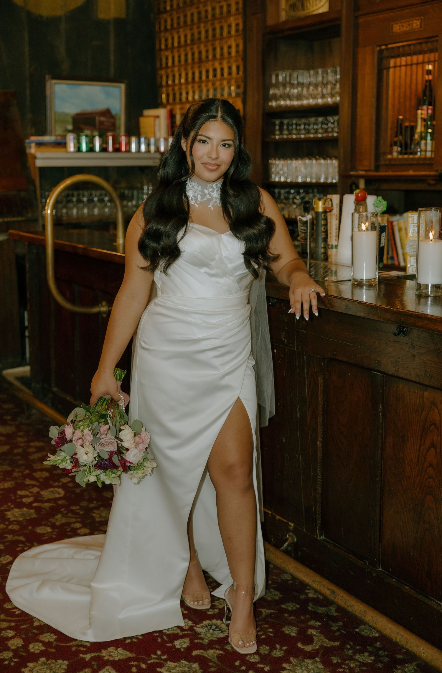 A bride poses with a floral bouquet against the backdrop of a classic wooden bar interior.