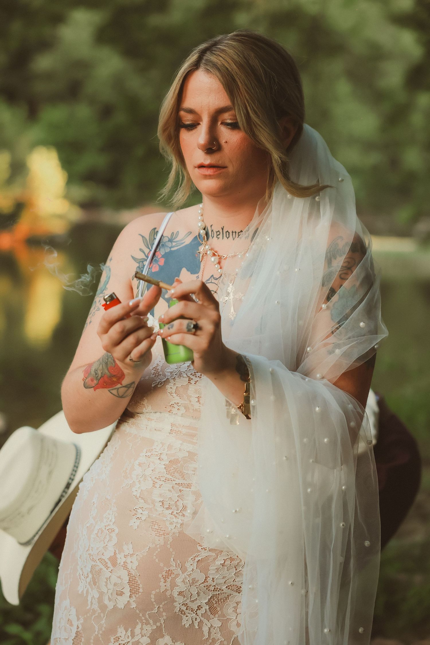 Person in a delicate lace wedding dress examining details outdoors in natural lighting.