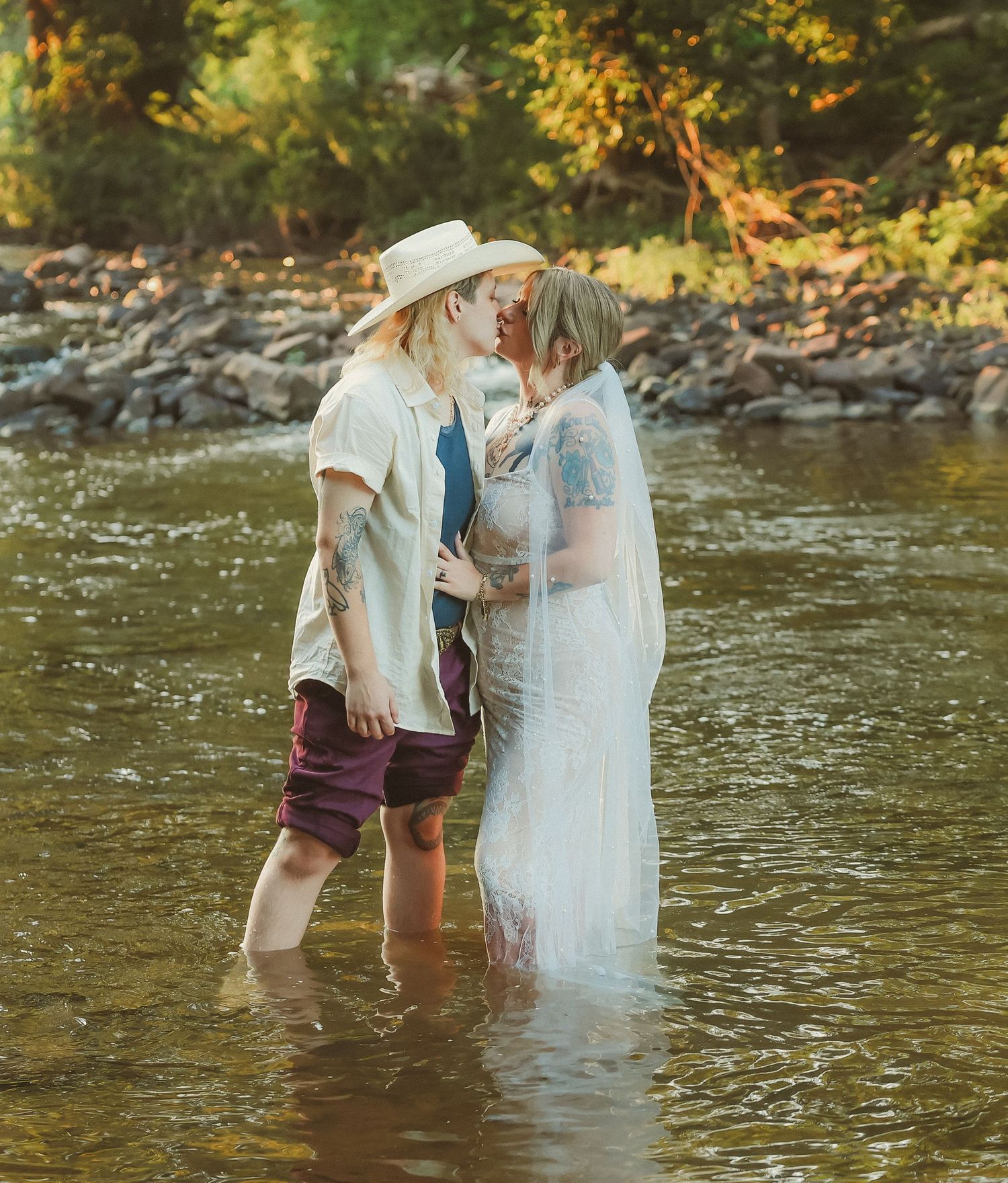A couple shares a tender moment while standing knee-deep in a river during their wedding shoot.