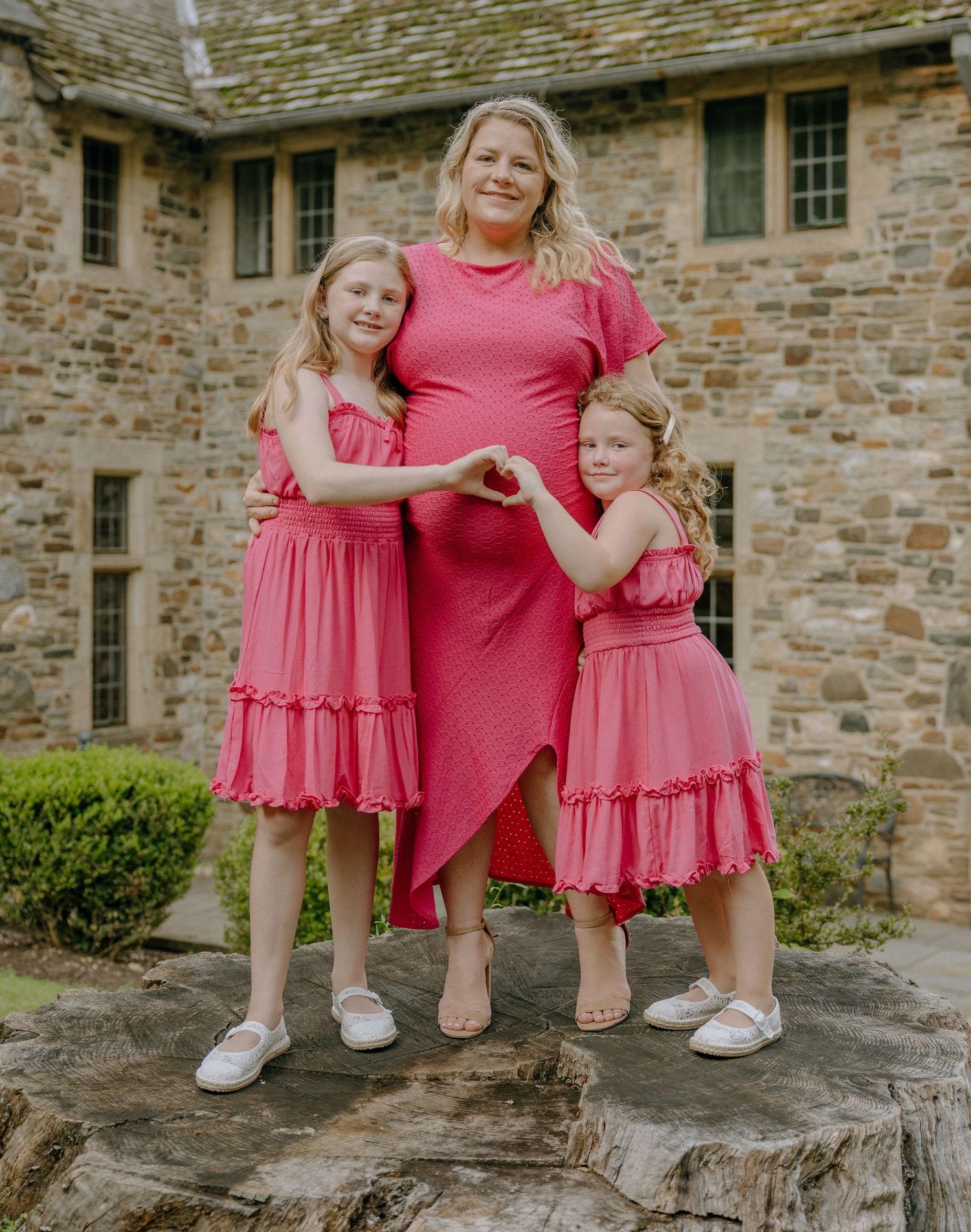 Candid family photo on stone steps showing matching pink dresses and casual pose.