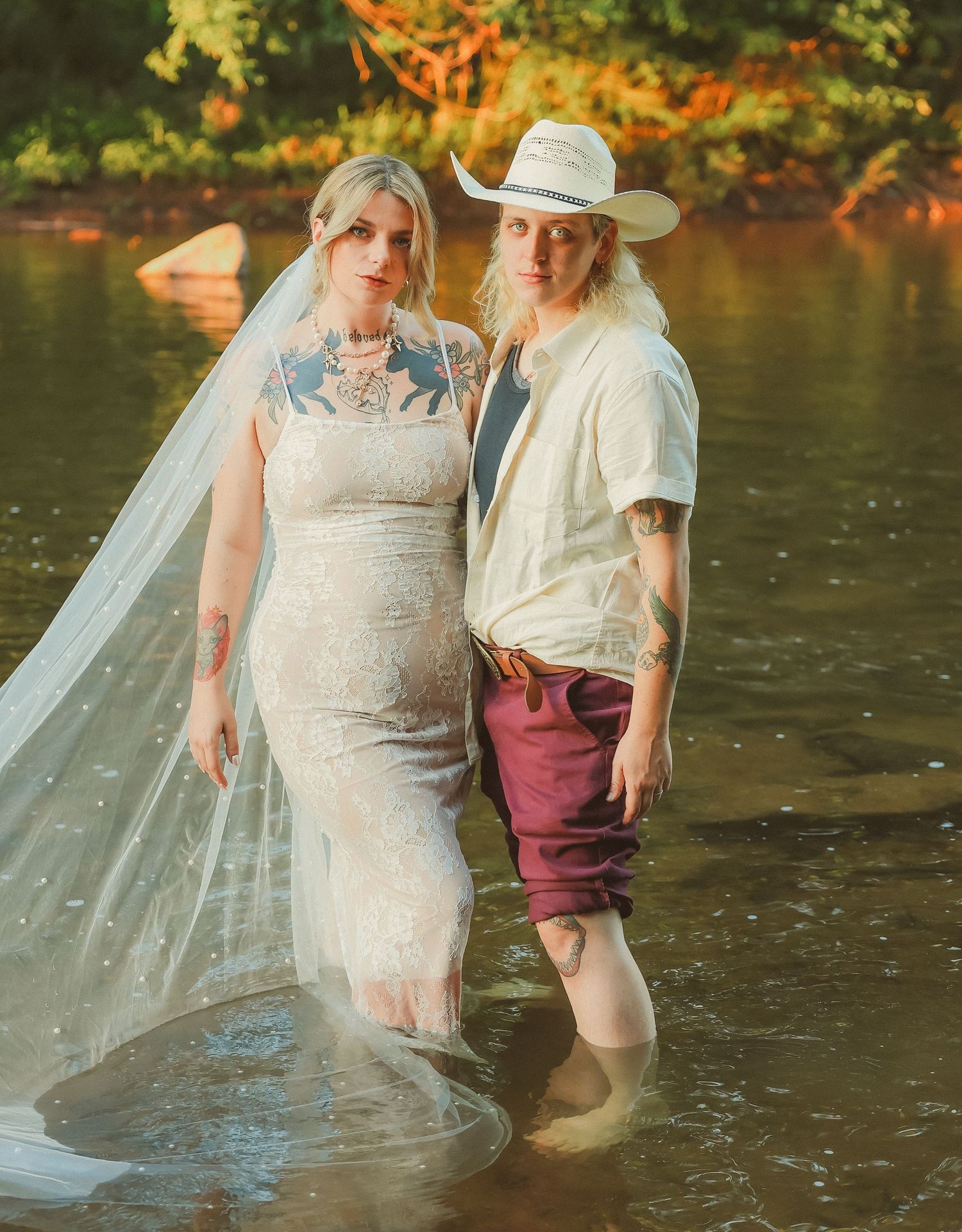 A couple poses together in shallow water during a wedding photoshoot.