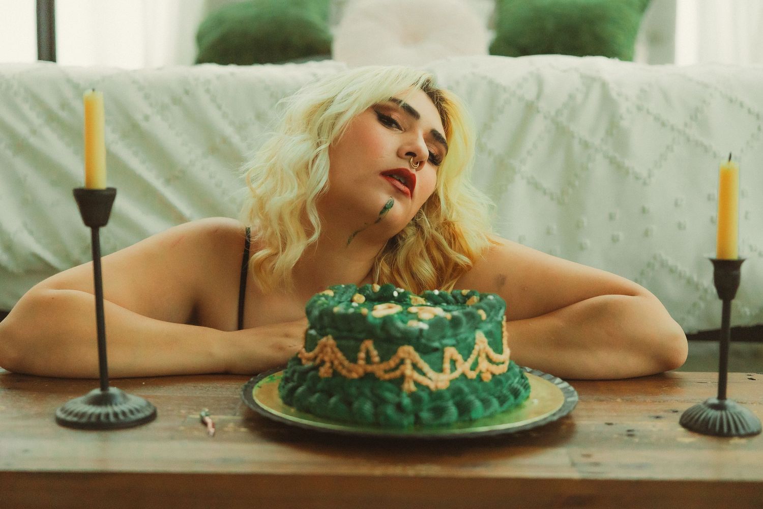 Styled photography featuring green frosted cake and candlesticks on white tablecloth.