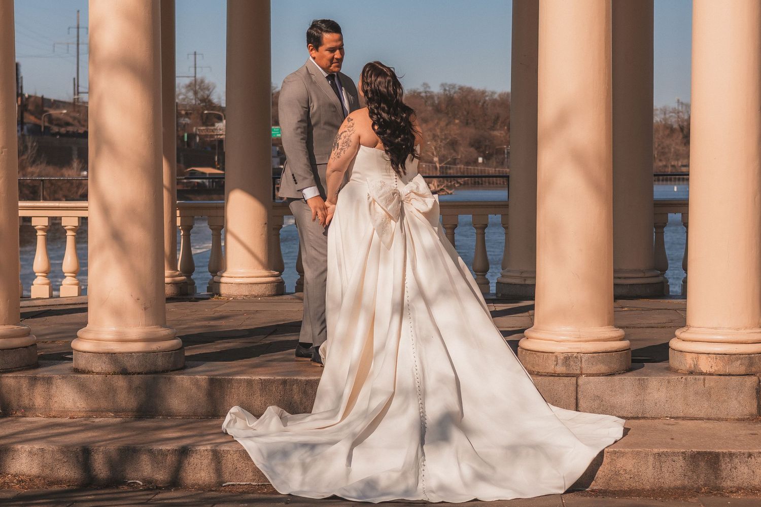 Wedding couple posing between classic stone columns with ornate architecture.