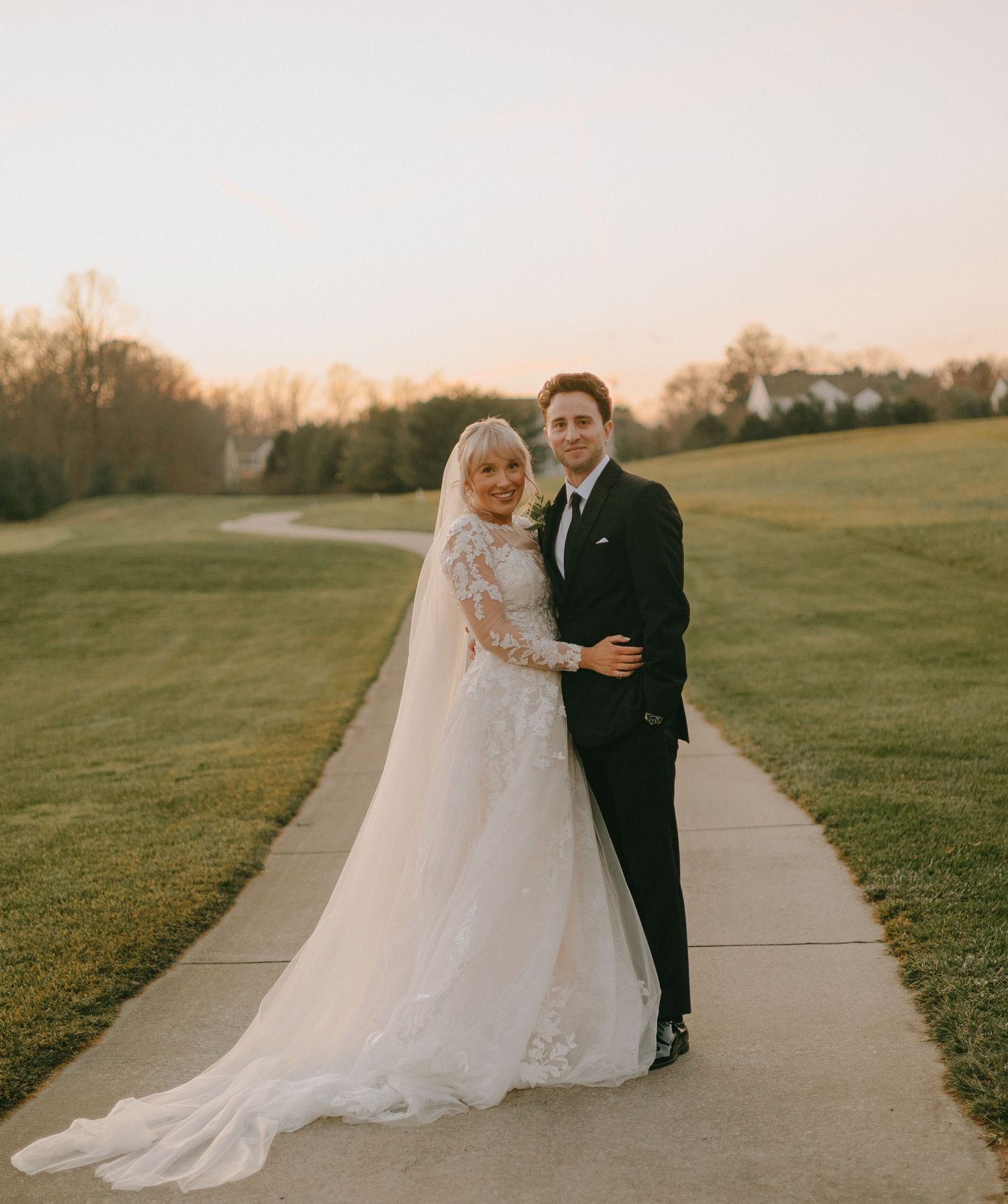 A couple shares a romantic moment while walking along a concrete path at dusk.
