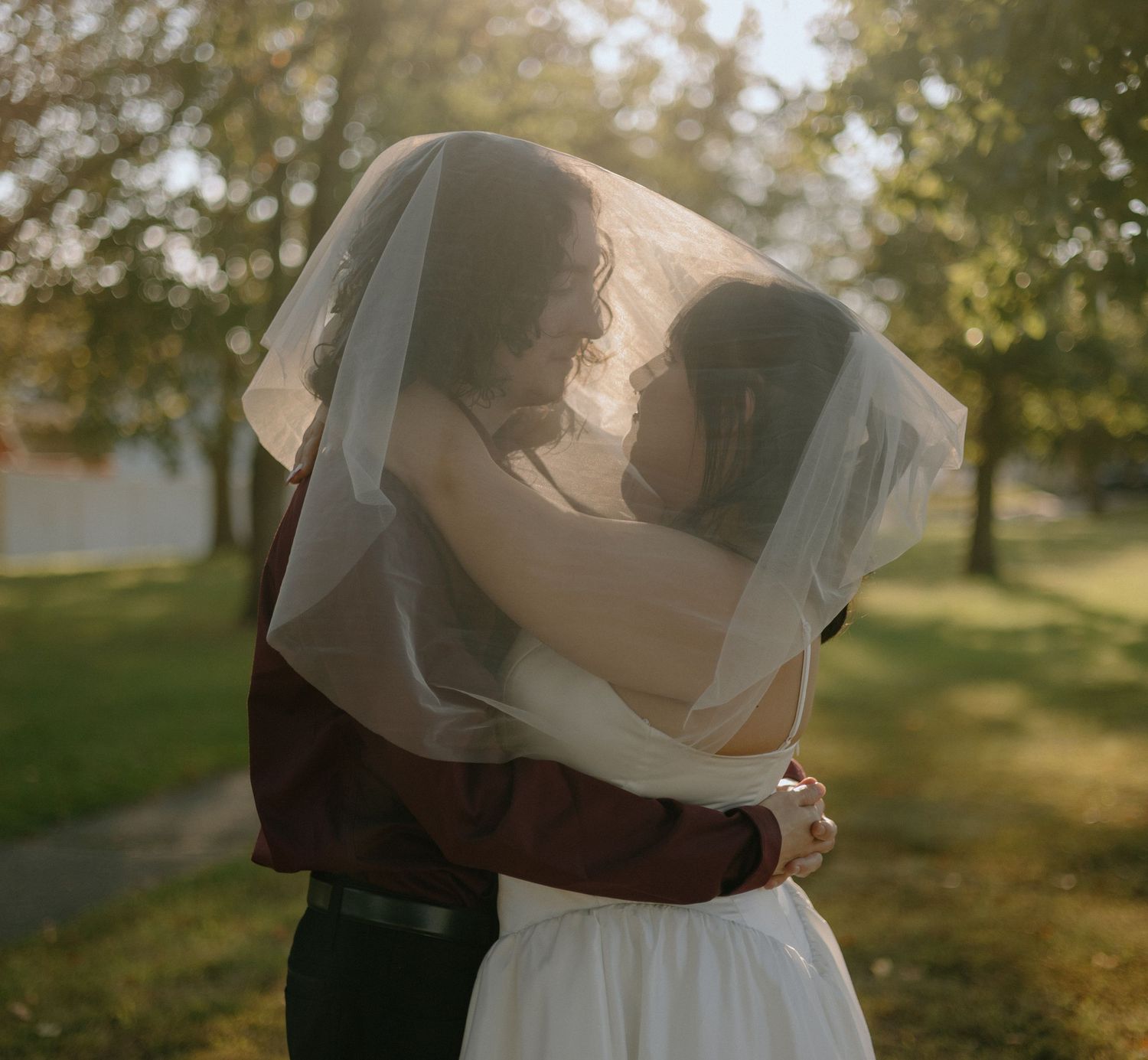 Soft sunlit wedding portraits captured in a dreamy outdoor setting with natural bokeh.