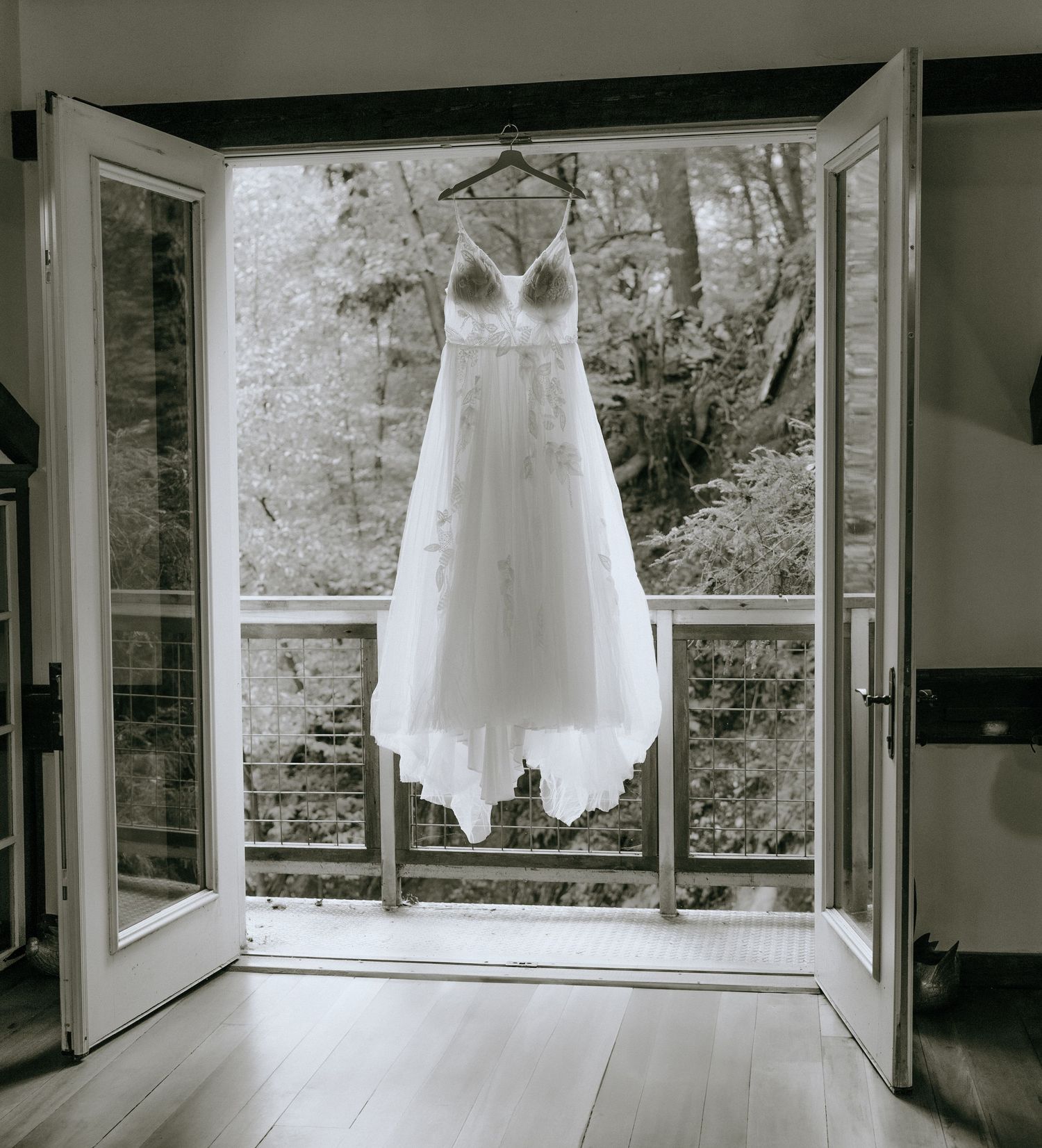 Multiple white wedding dresses displayed in a bright sunroom with panoramic windows.