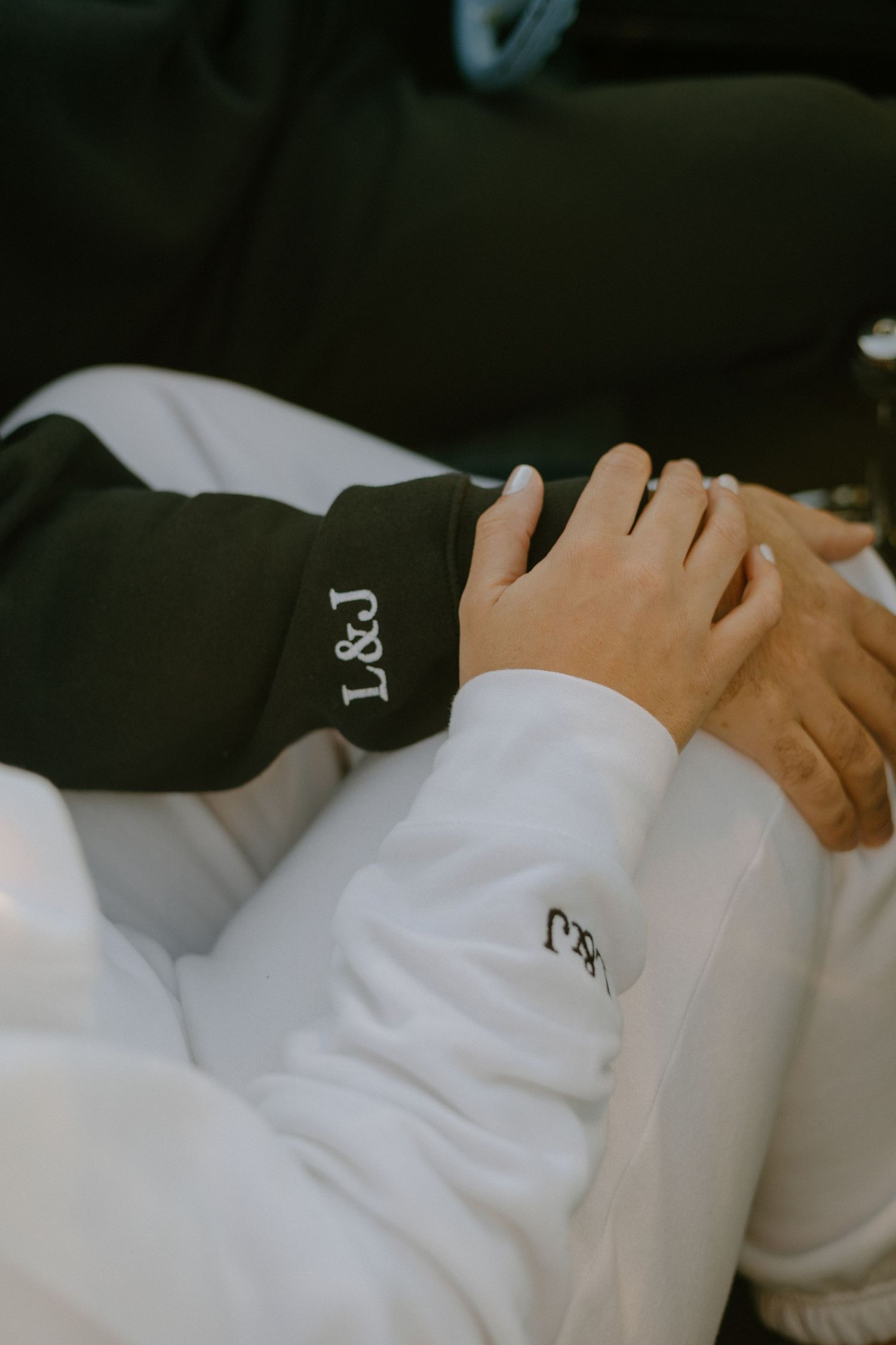 Close-up view of hands resting on white bedding in a dimly lit room.