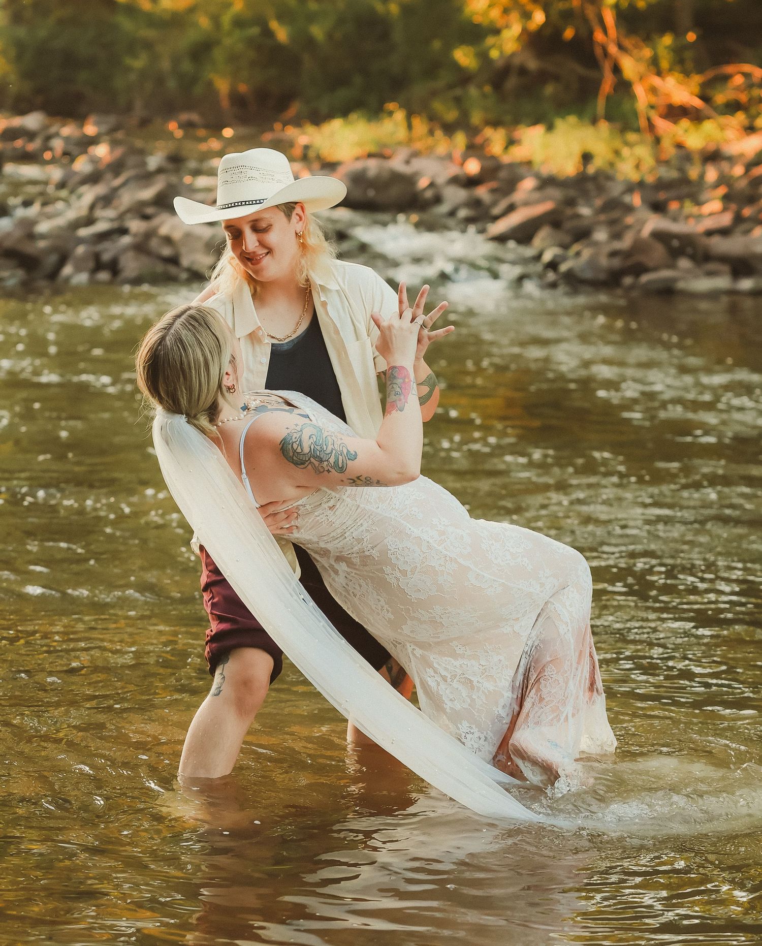 A couple embraces while standing in a river during their wedding photo session.