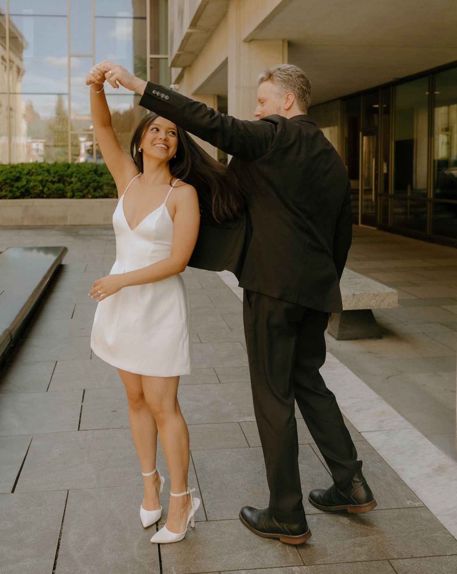 Dancing couple in formal wear striking poses on an outdoor patio.