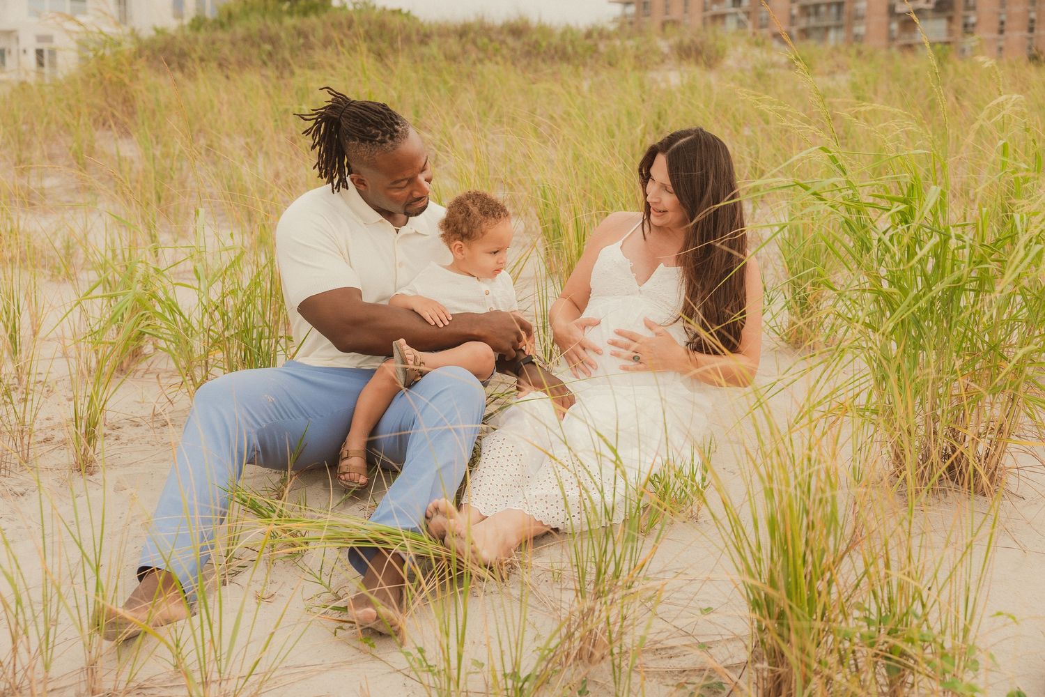 Family photoshoot in natural beach grass with warm sunset lighting.