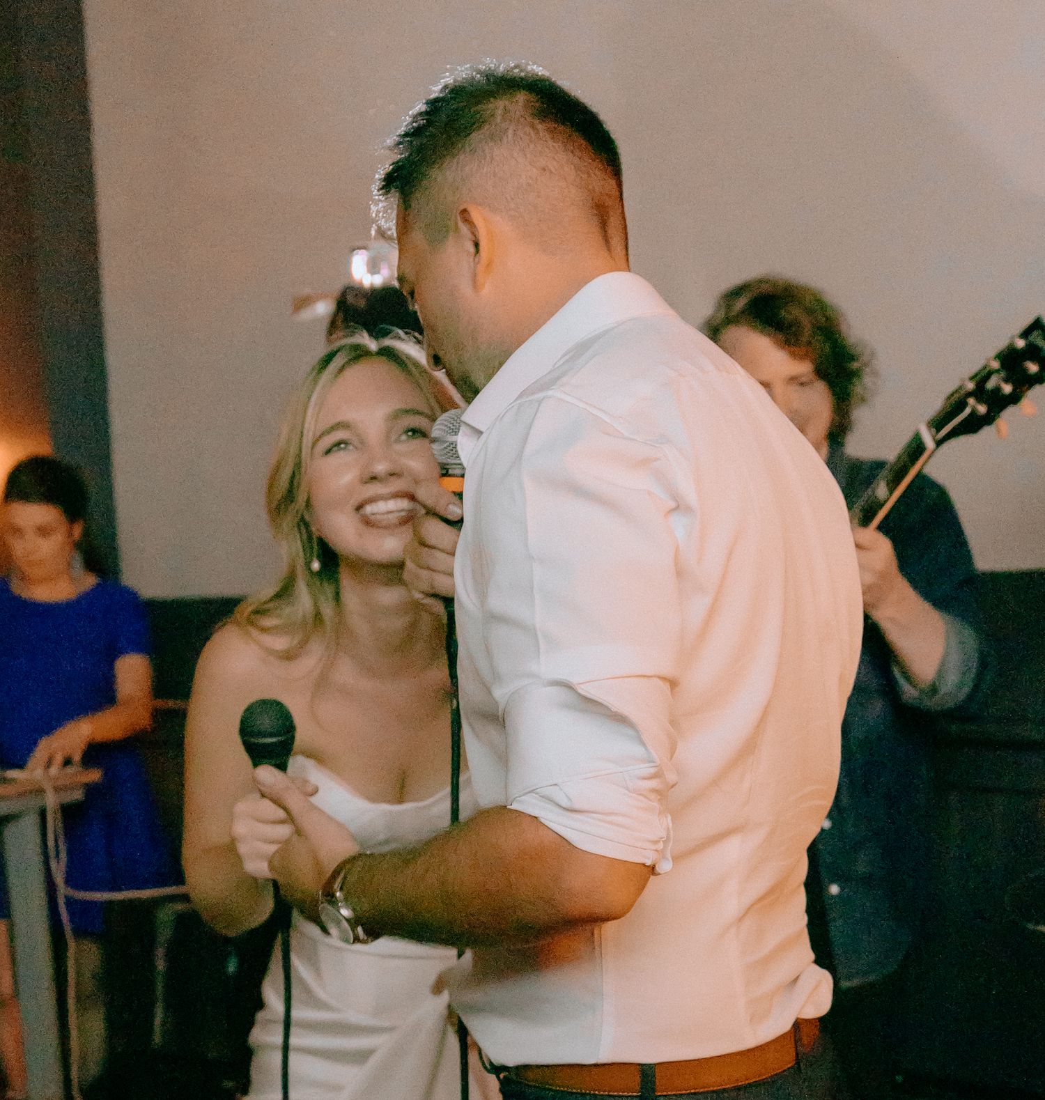 Newlyweds singing and laughing together during a wedding reception karaoke performance.