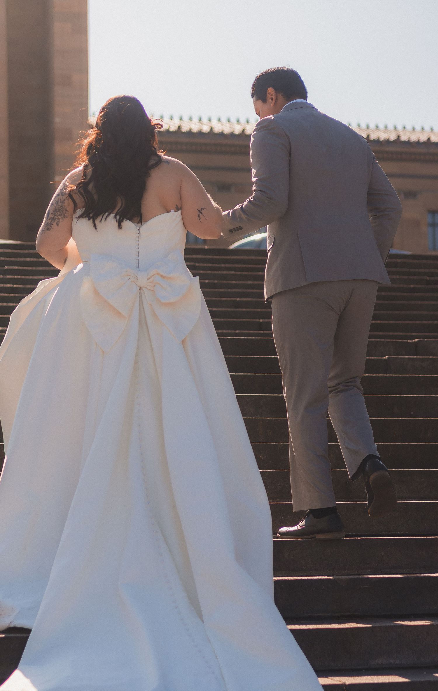 Wedding couple ascending stone steps with bride's dramatic white gown trailing behind.