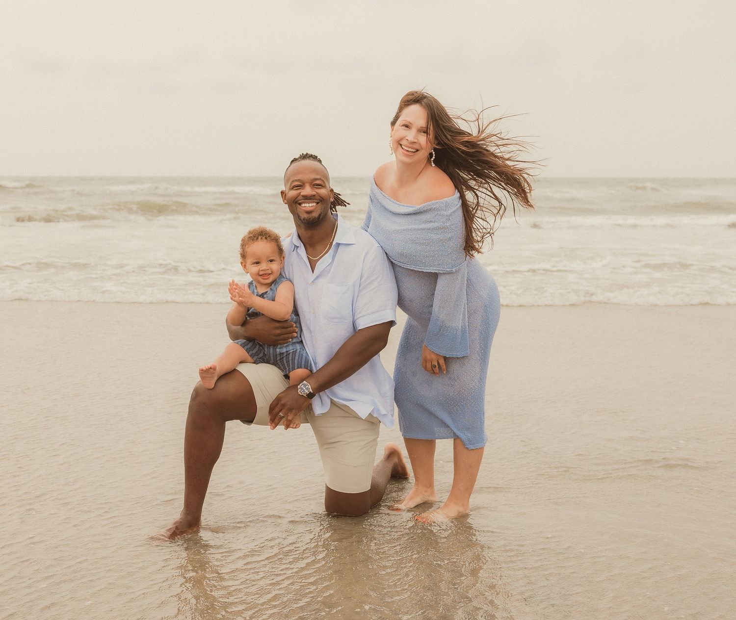 Family enjoying tender moments together on beach at sunset.
