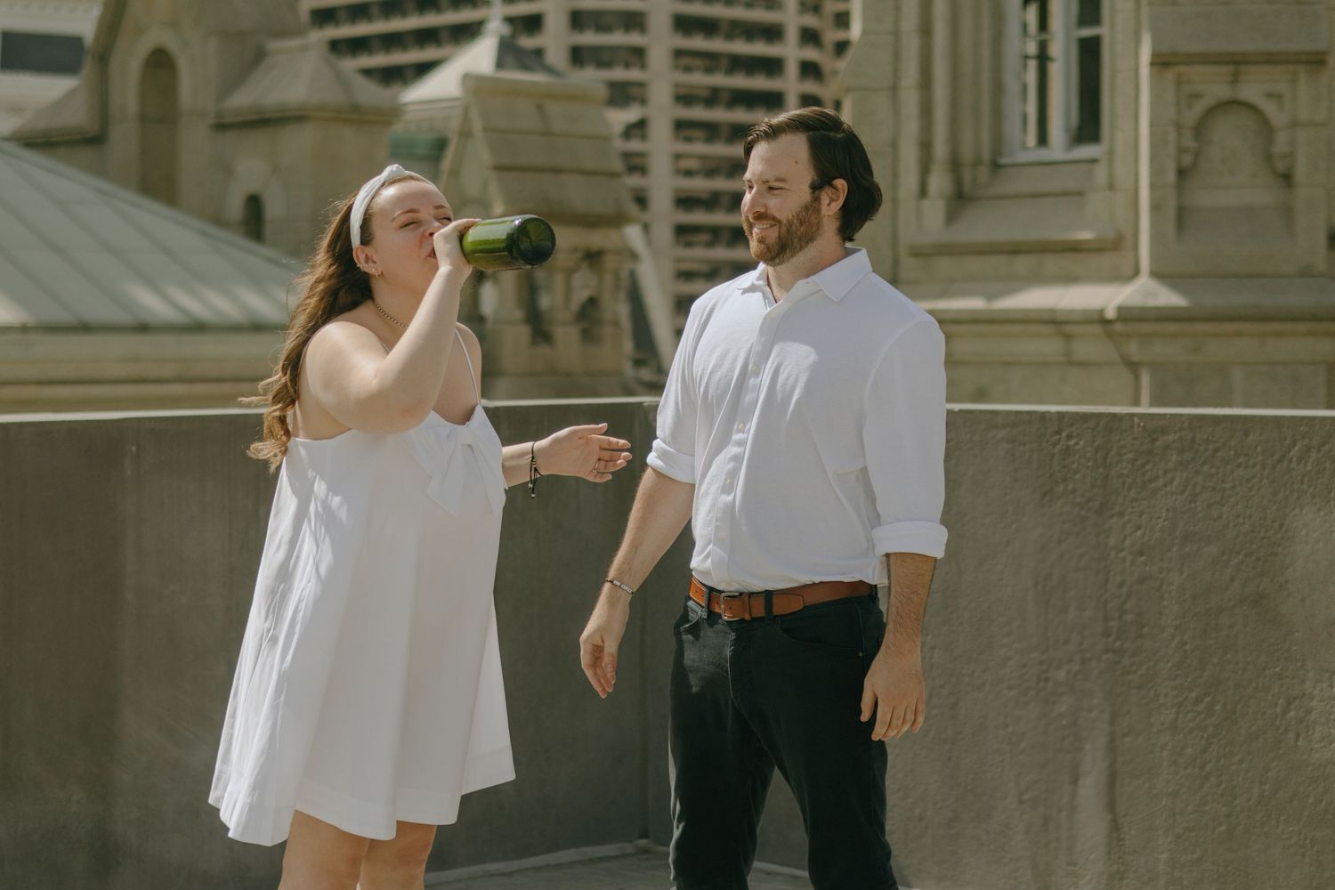 Elegant couple in white and black attire share intimate moments on stone steps of historic building.