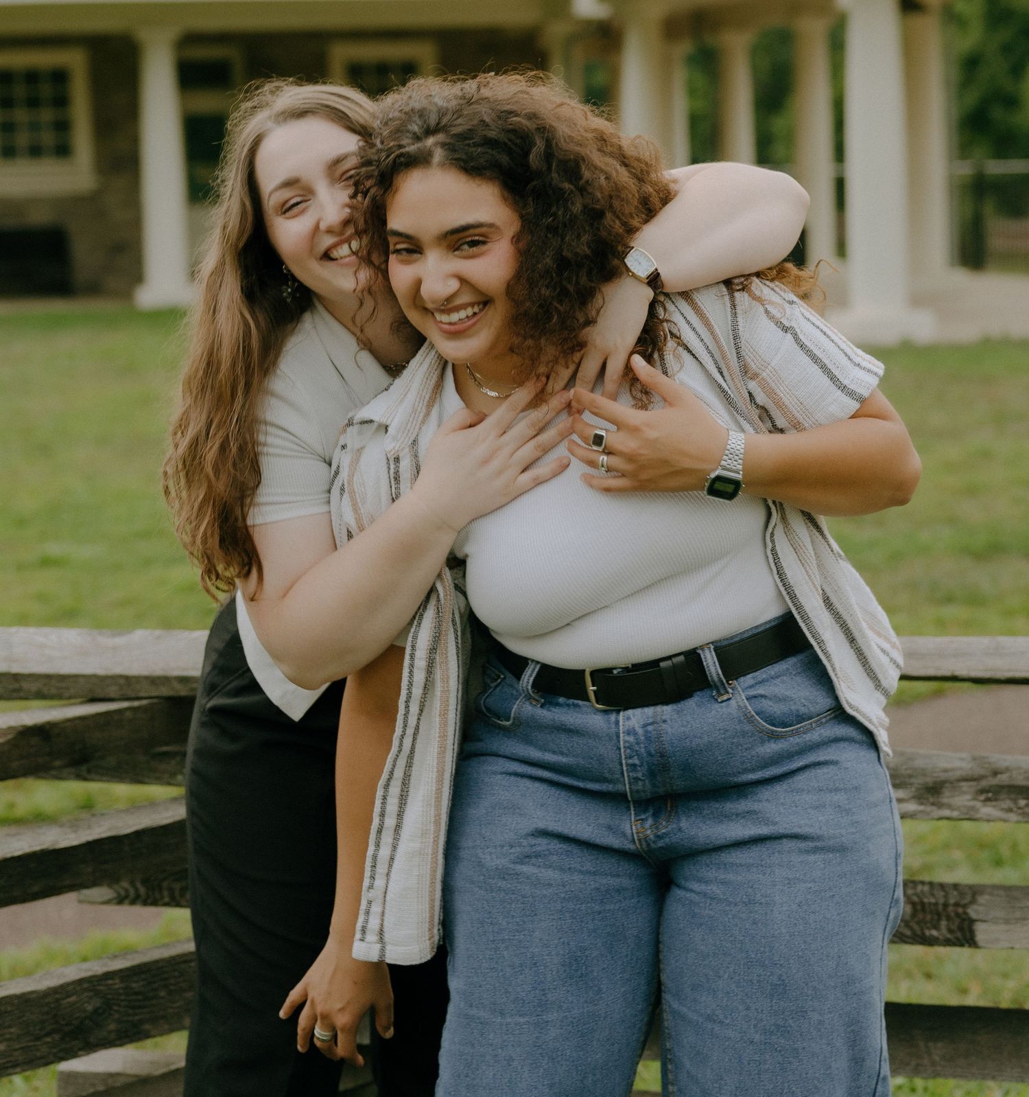 Close-up of two friends sharing a joyful moment while sitting outdoors.