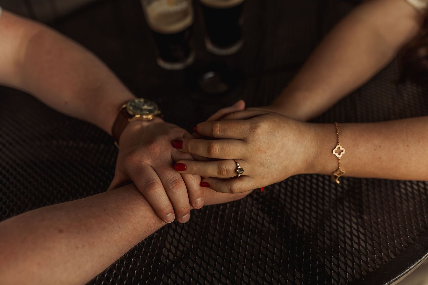 Close-up shot of hands with jewelry resting on textured dark fabric.