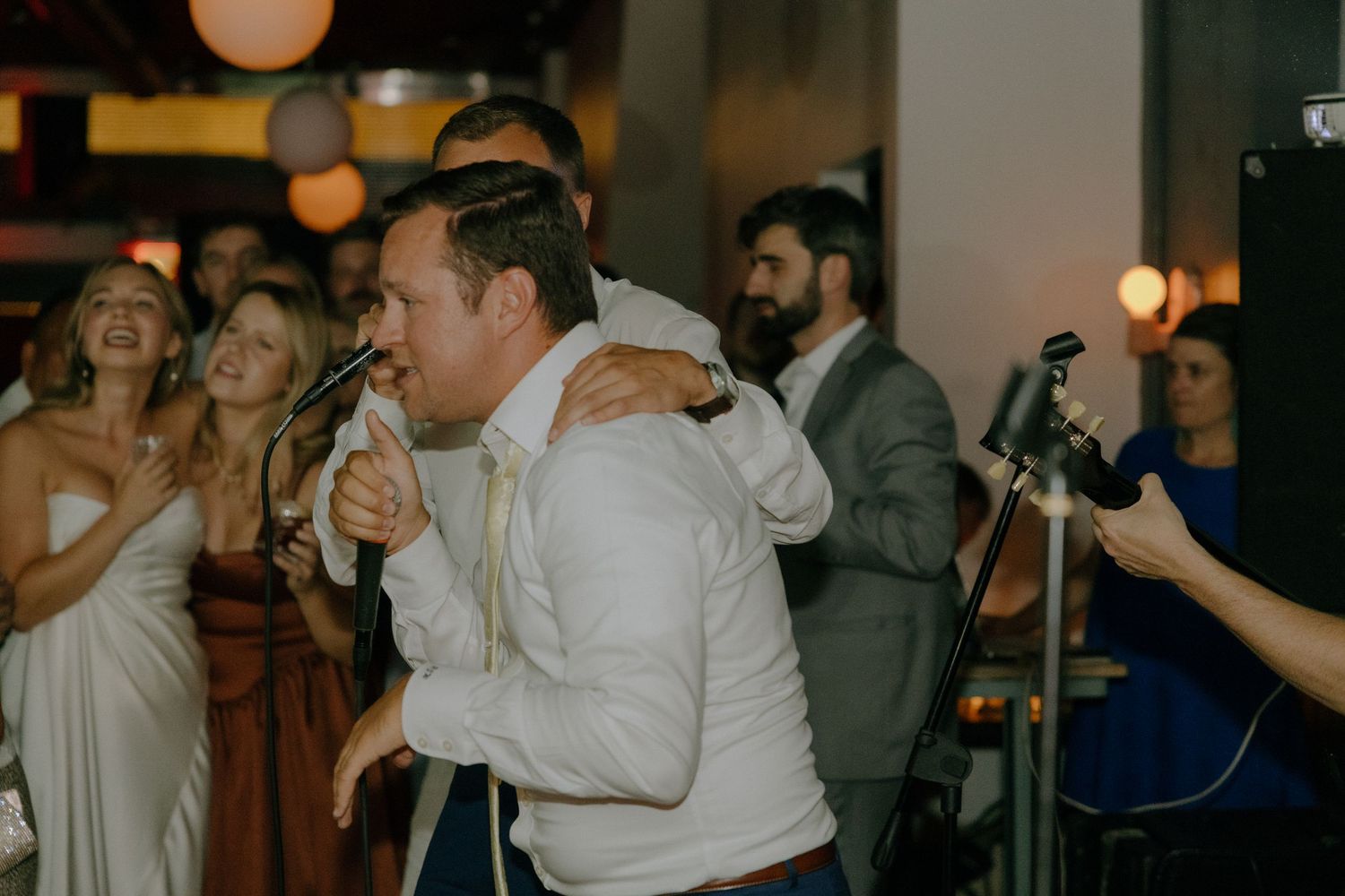 Dance floor moments captured during a lively wedding reception with atmospheric lighting.