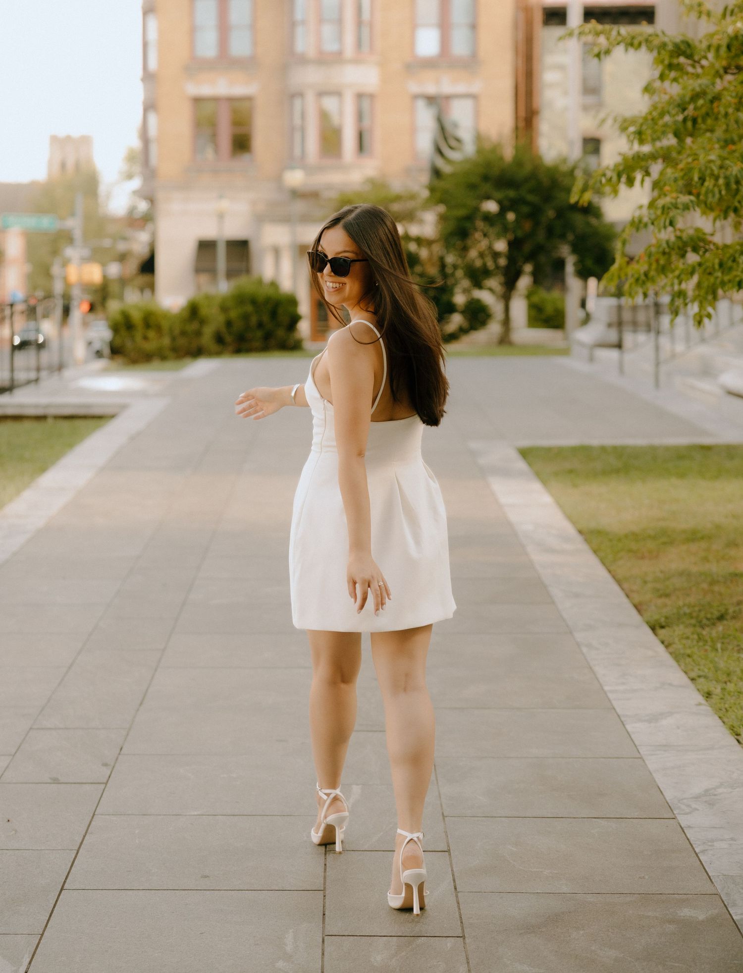 White dress and heels walking along stone pathway near historic building.