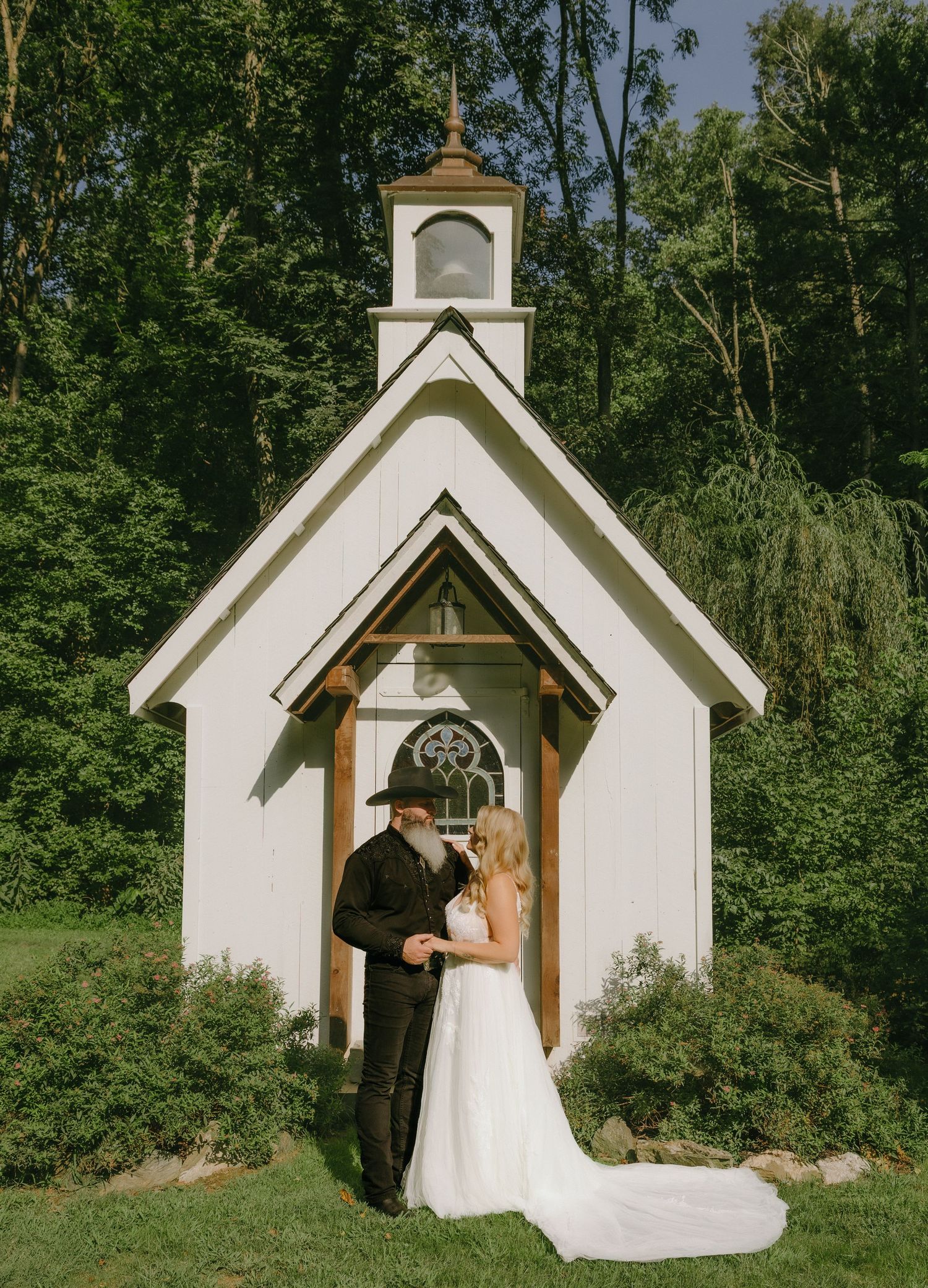 Sequence of bride entering small white chapel surrounded by trees.