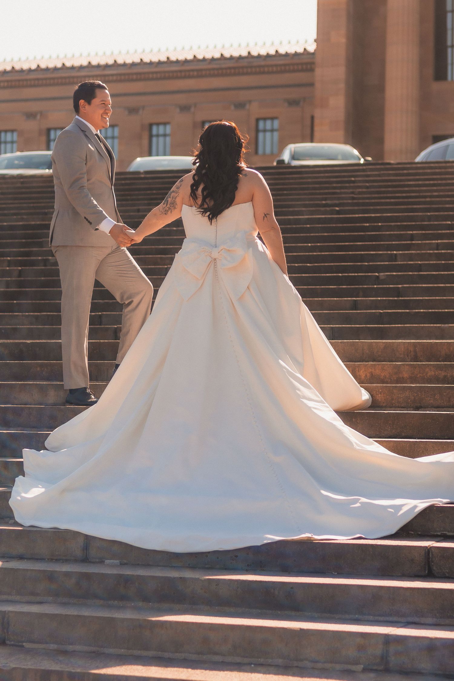 Wedding couple photographed on grand stone steps of historic building at sunset.