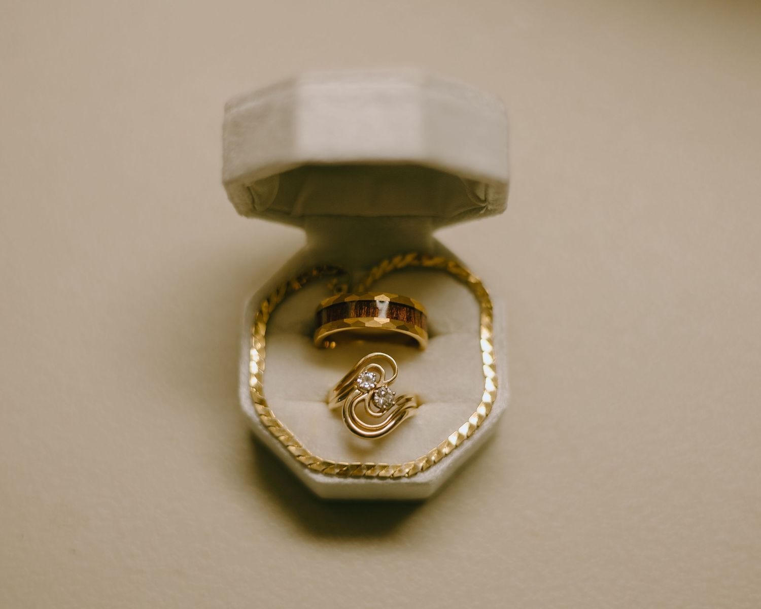 Gold wedding ring shown in multiple angles on a beige surface, displaying its intricate design and craftsmanship.